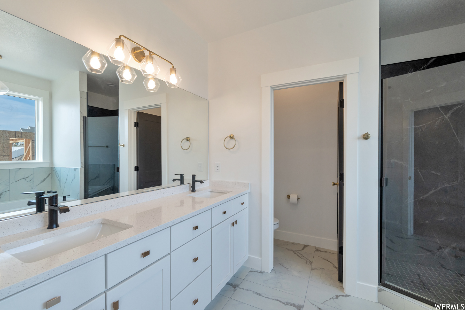 Full bathroom featuring tile floors, toilet, mirror, enclosed shower, and dual vanity
