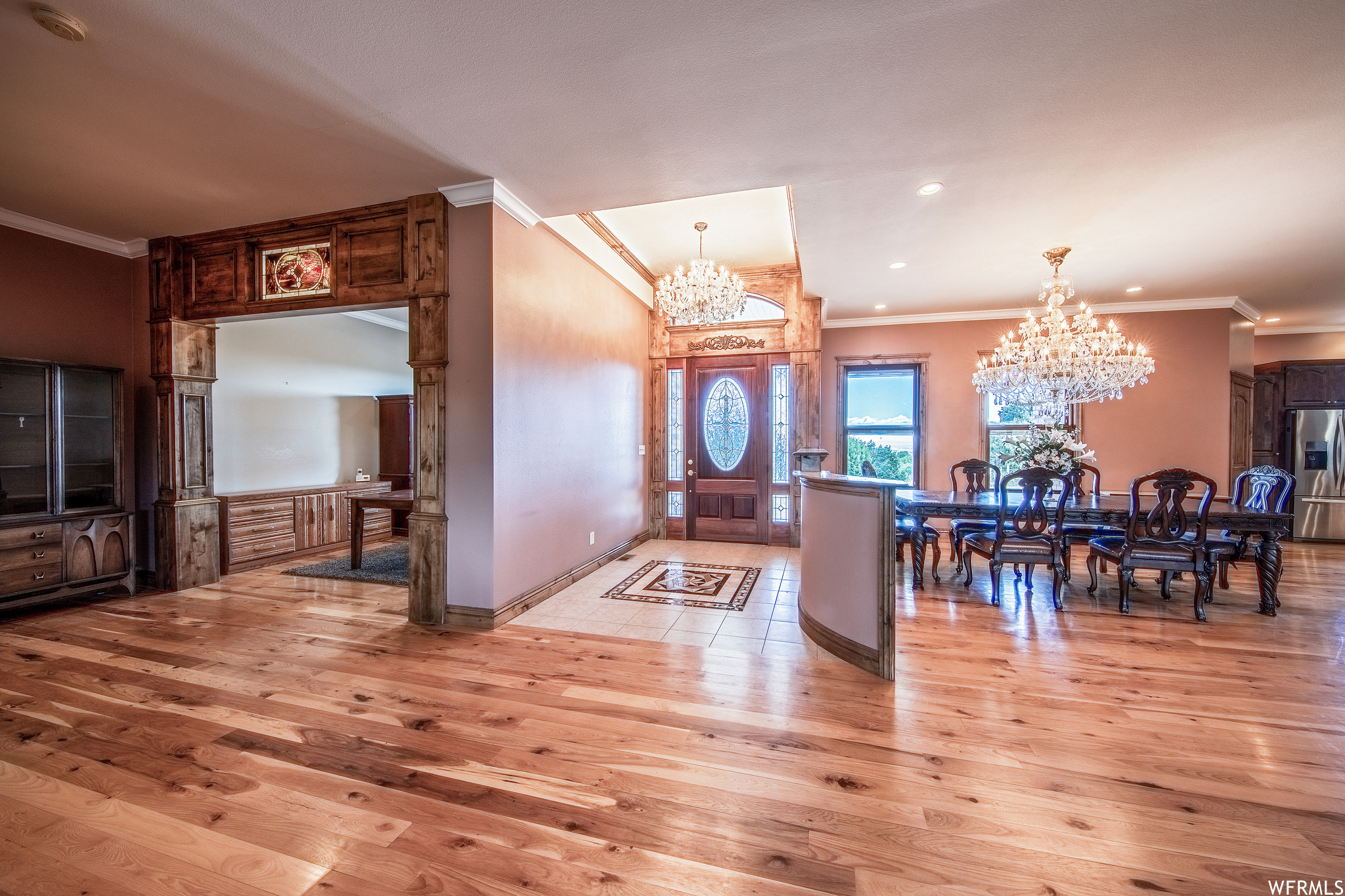 Kitchen with a notable chandelier, refrigerator, granite-like countertops, pendant lighting, light hardwood flooring, and dark brown cabinetry