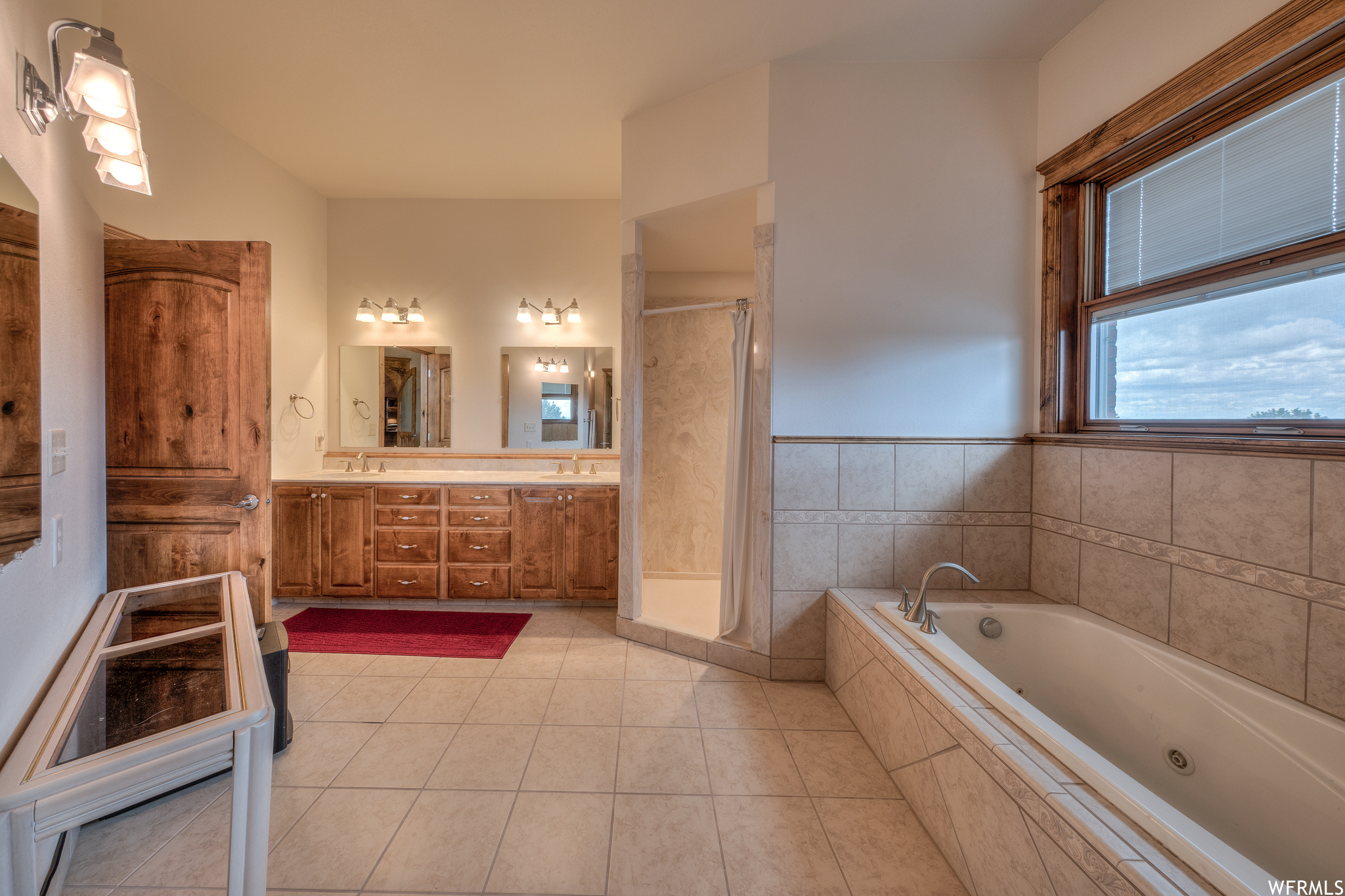 Bathroom featuring natural light, independent shower and bath, mirror, and dual bowl vanity