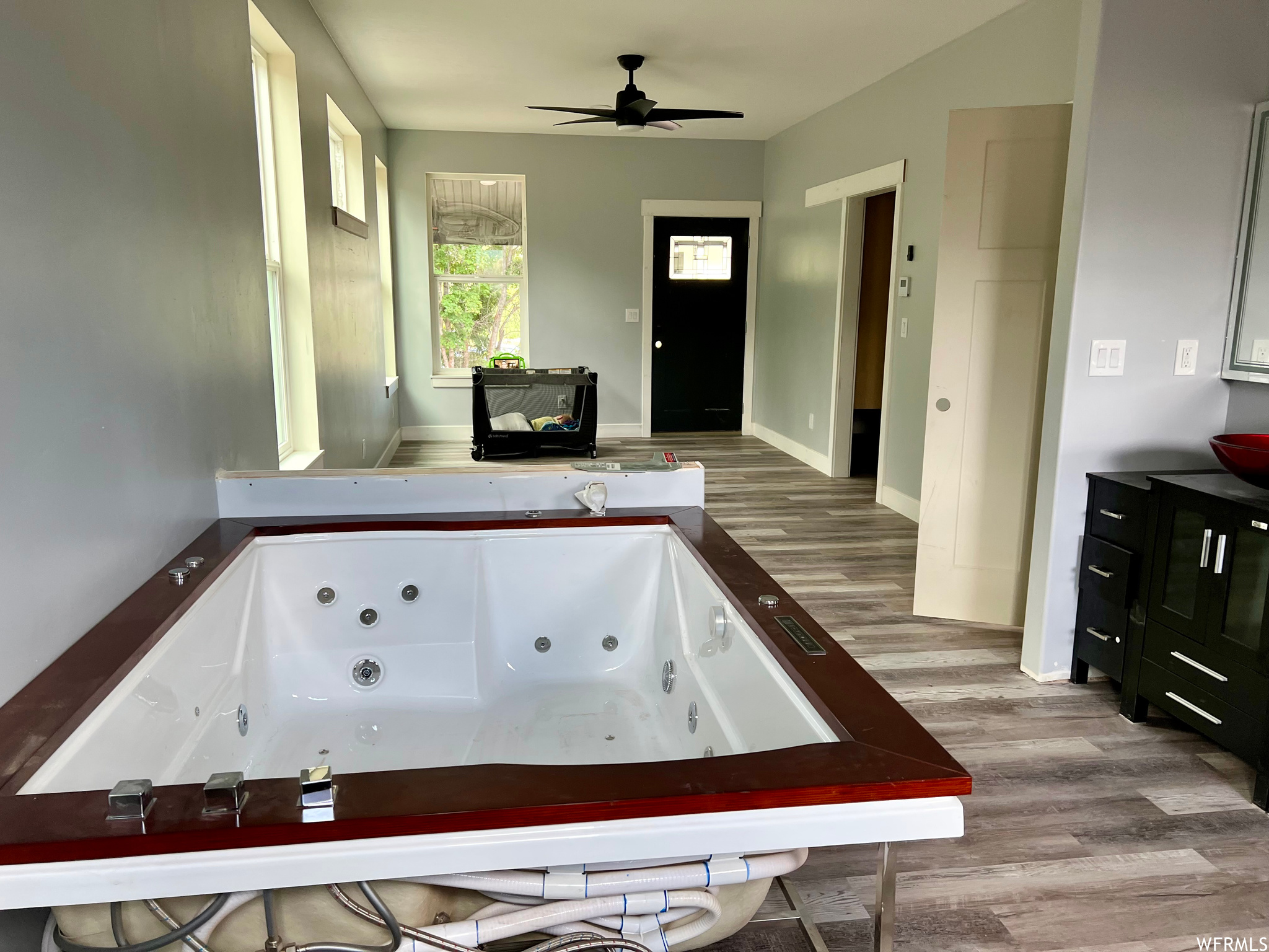 Bathroom with a ceiling fan, hardwood flooring, and a bathtub