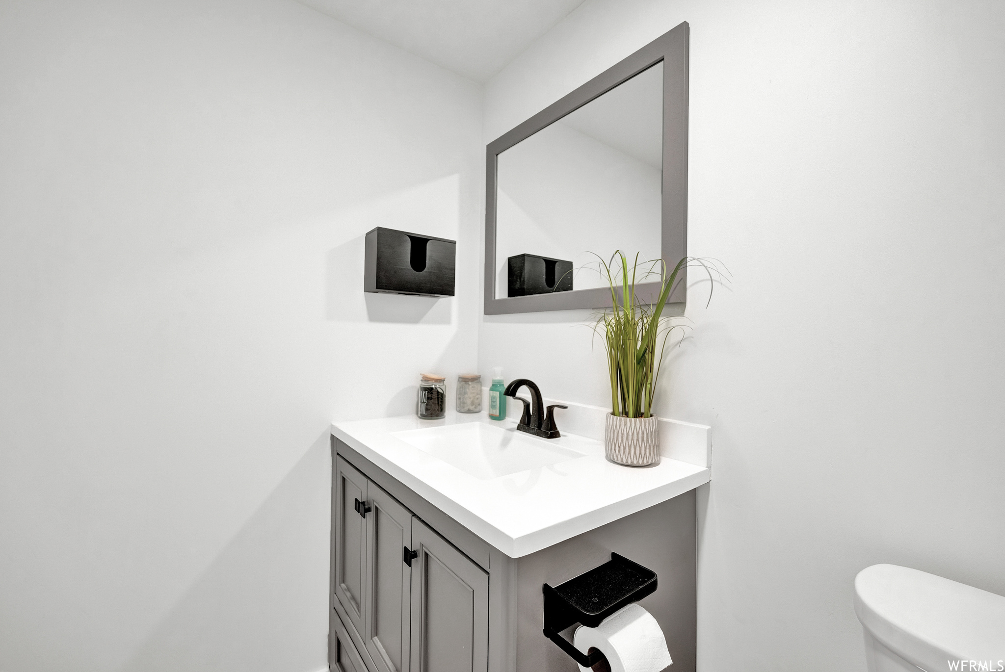 Half bath featuring vanity with extensive cabinet space, mirror, and toilet