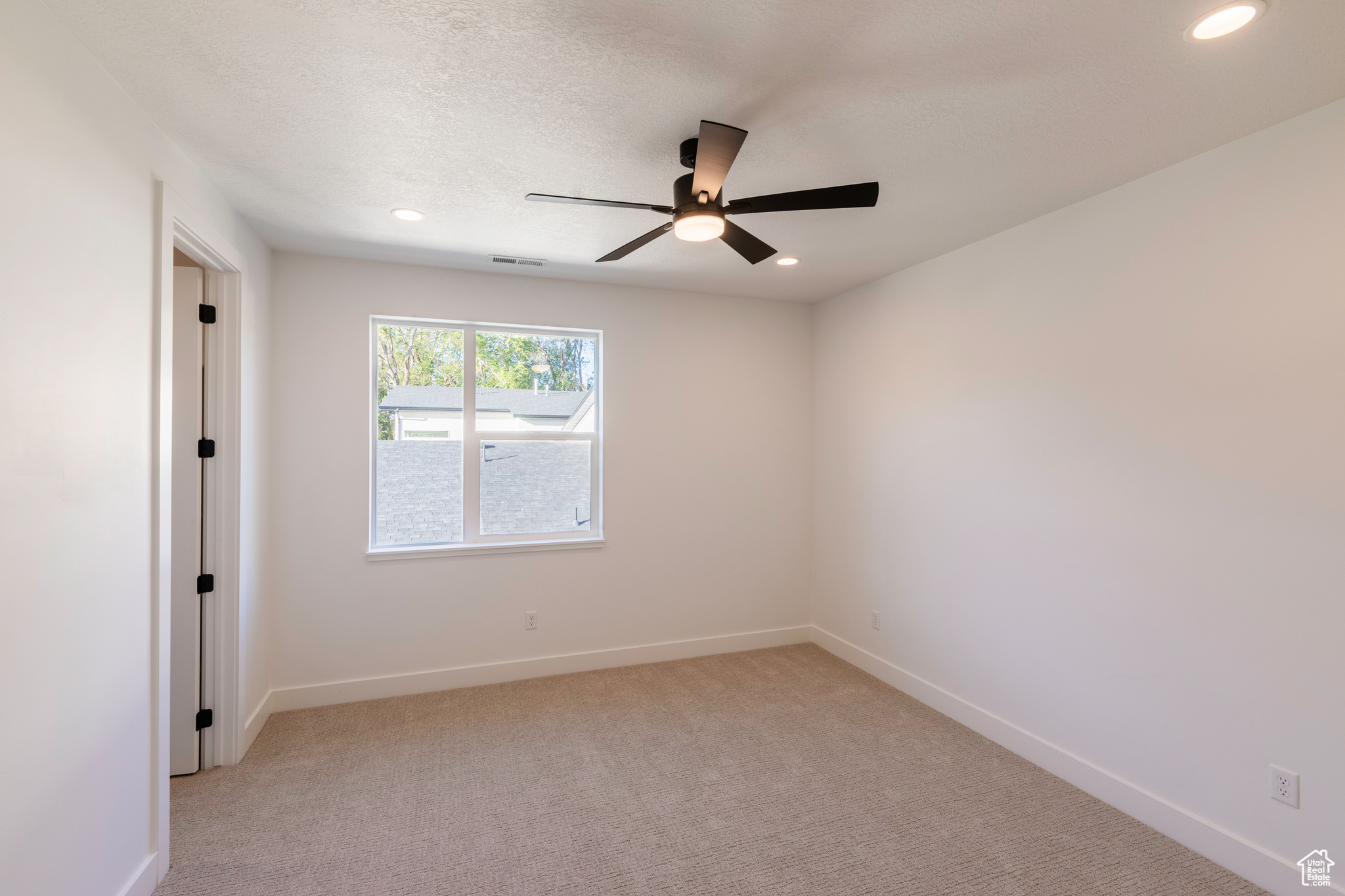 Empty room featuring light carpet and ceiling fan