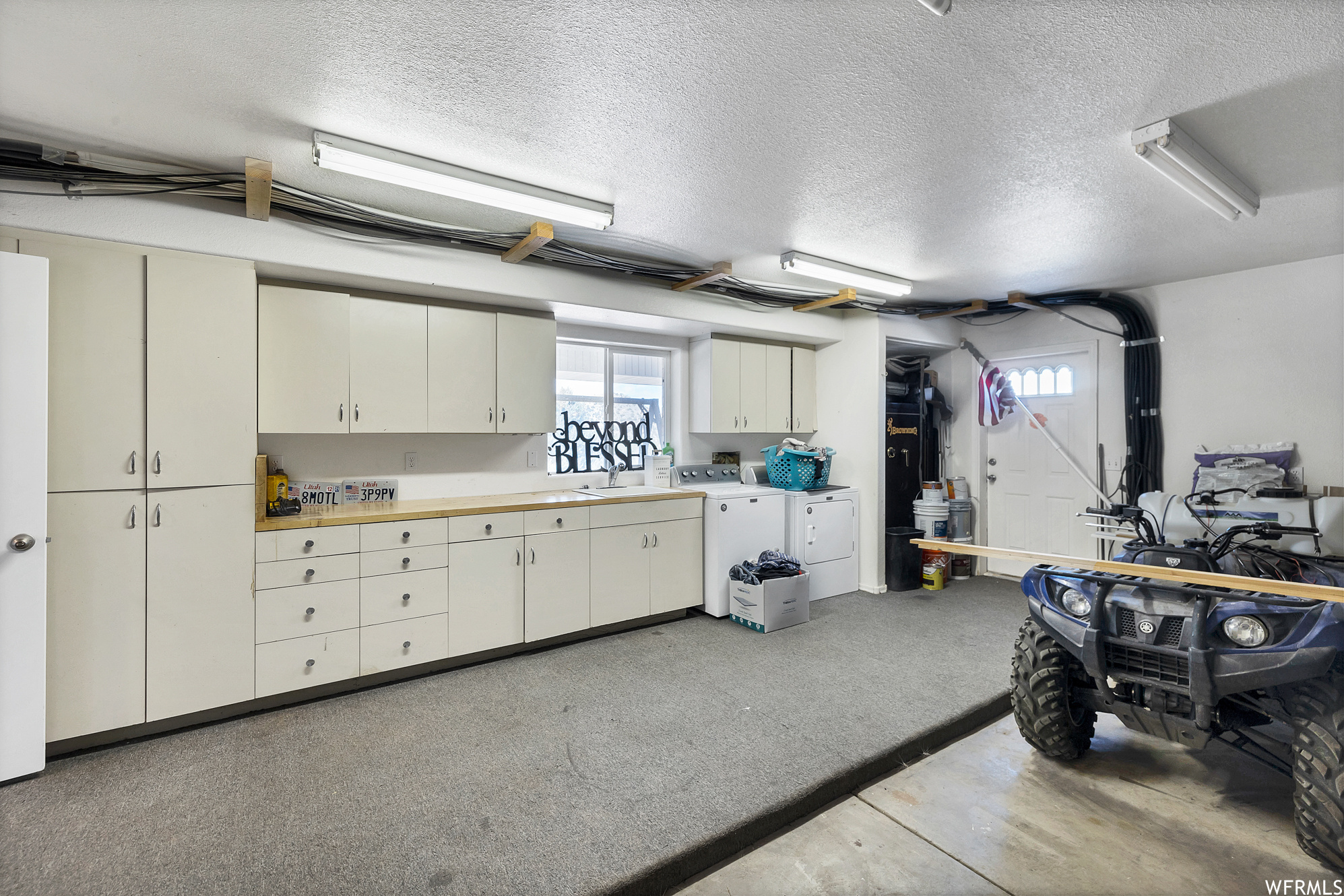 Garage featuring washer / dryer, light floors, and white cabinets