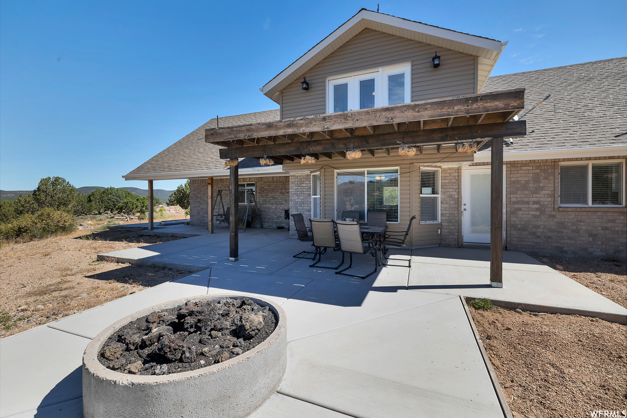 Back of property with fire pit and a pergola