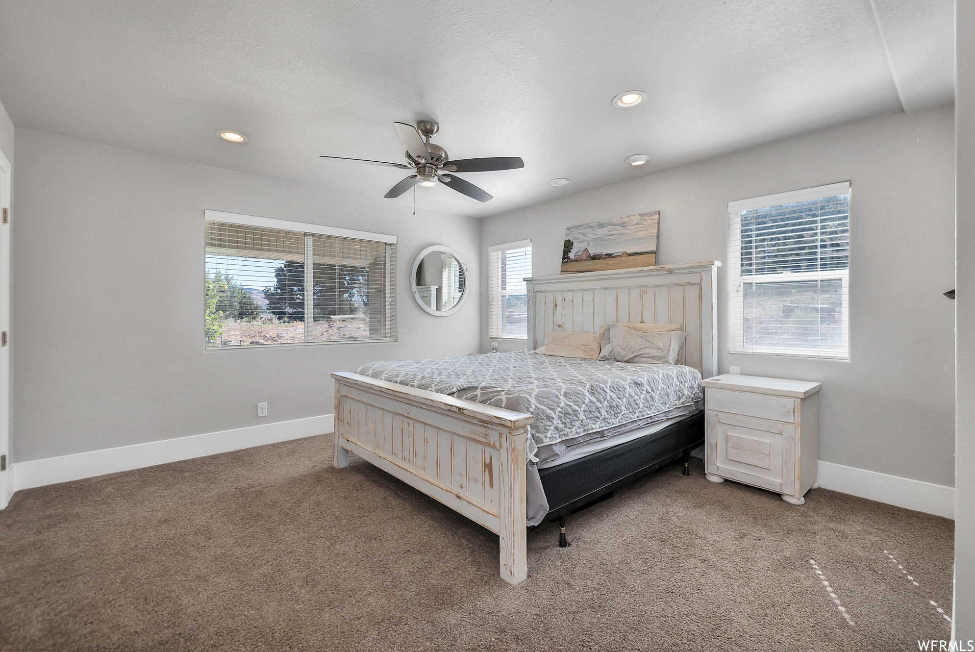 Carpeted bedroom featuring a ceiling fan and natural light
