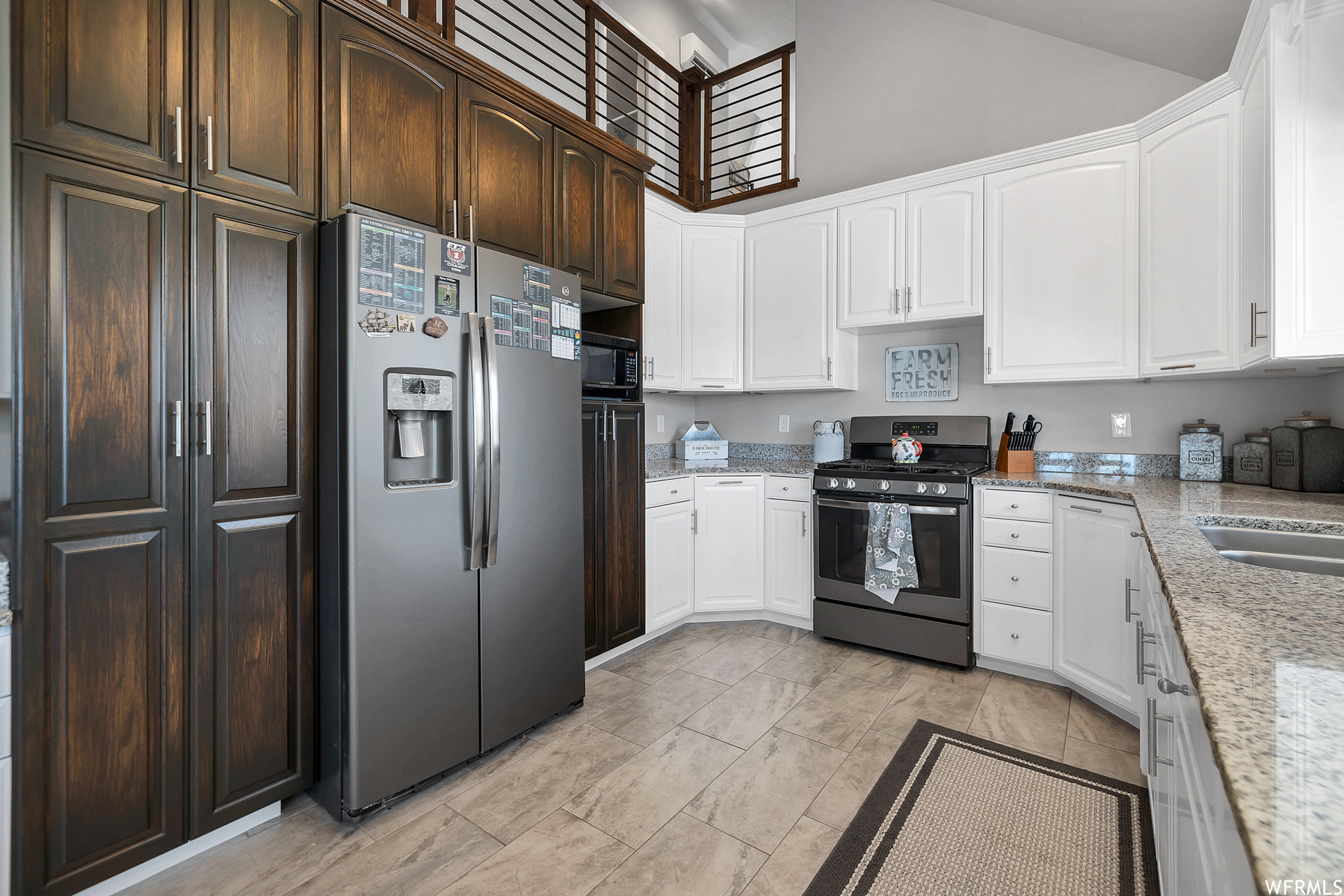 Kitchen with refrigerator, range oven, light tile flooring, and white cabinetry