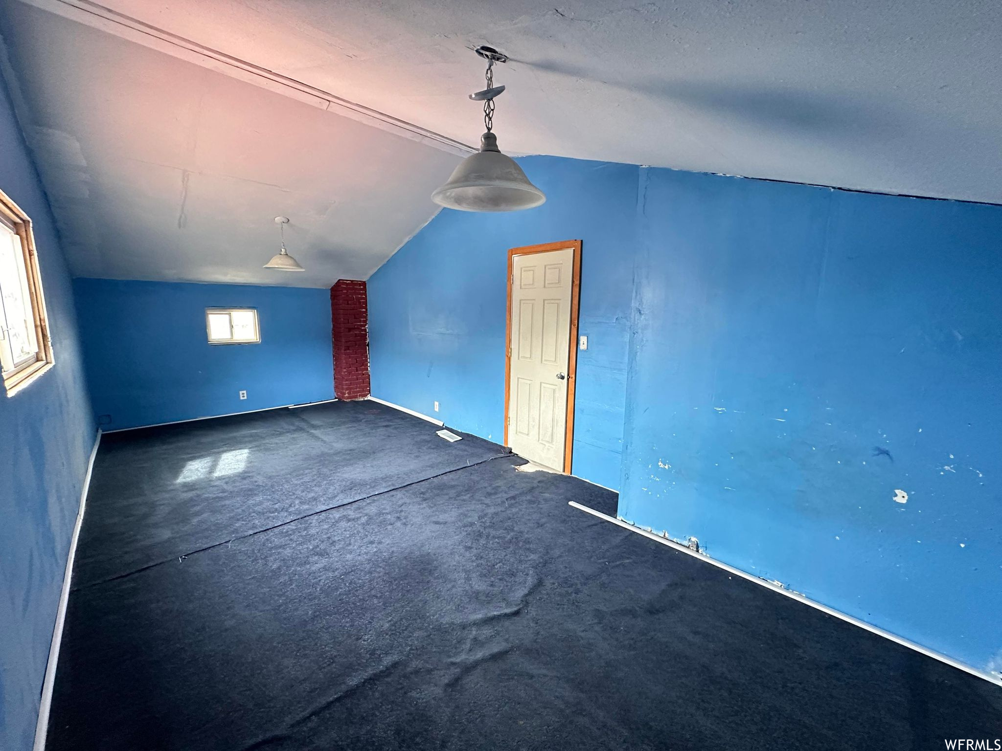 Empty room with dark carpet and lofted ceiling