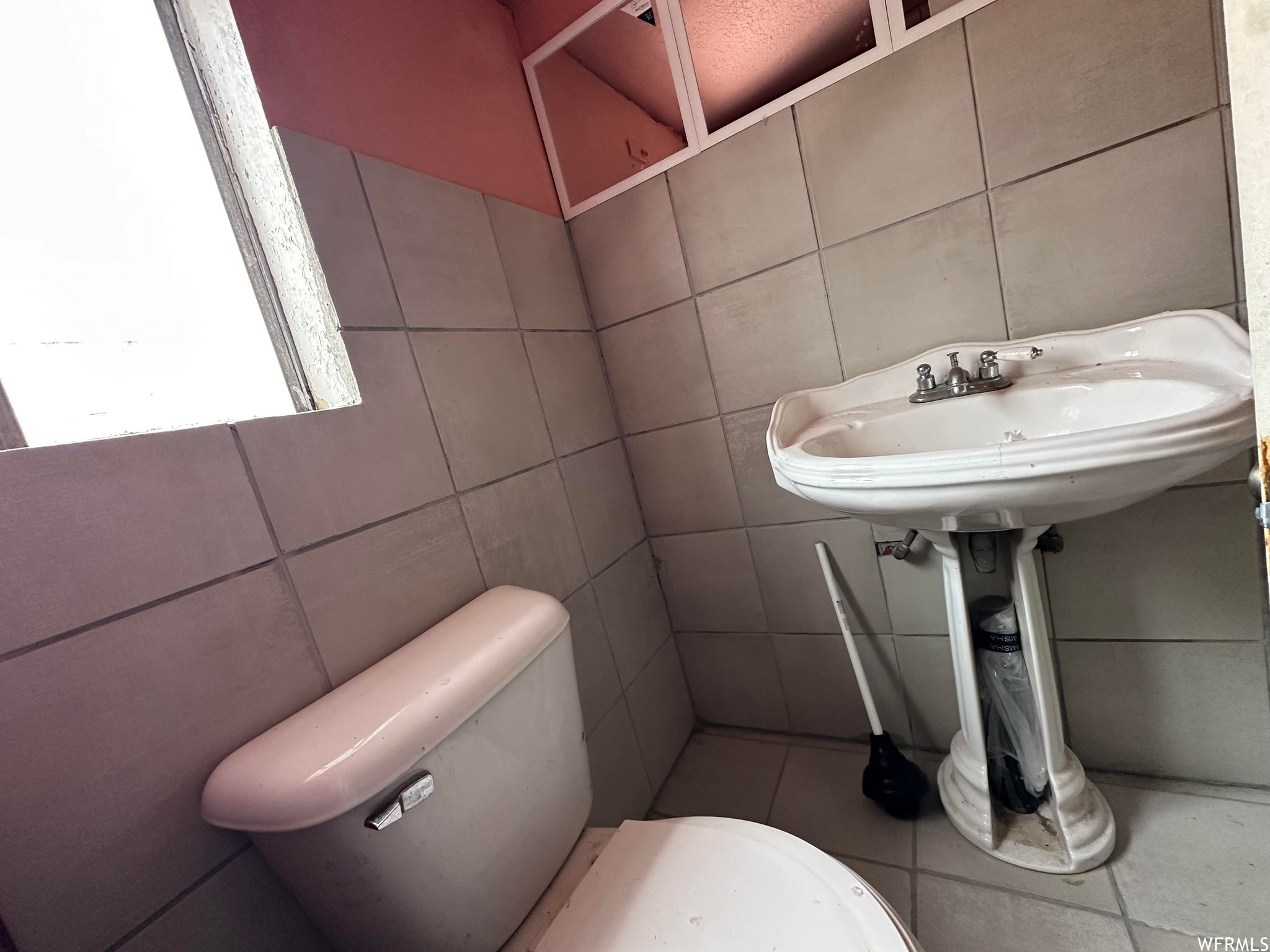 Bathroom with tile flooring, toilet, tile walls, and sink