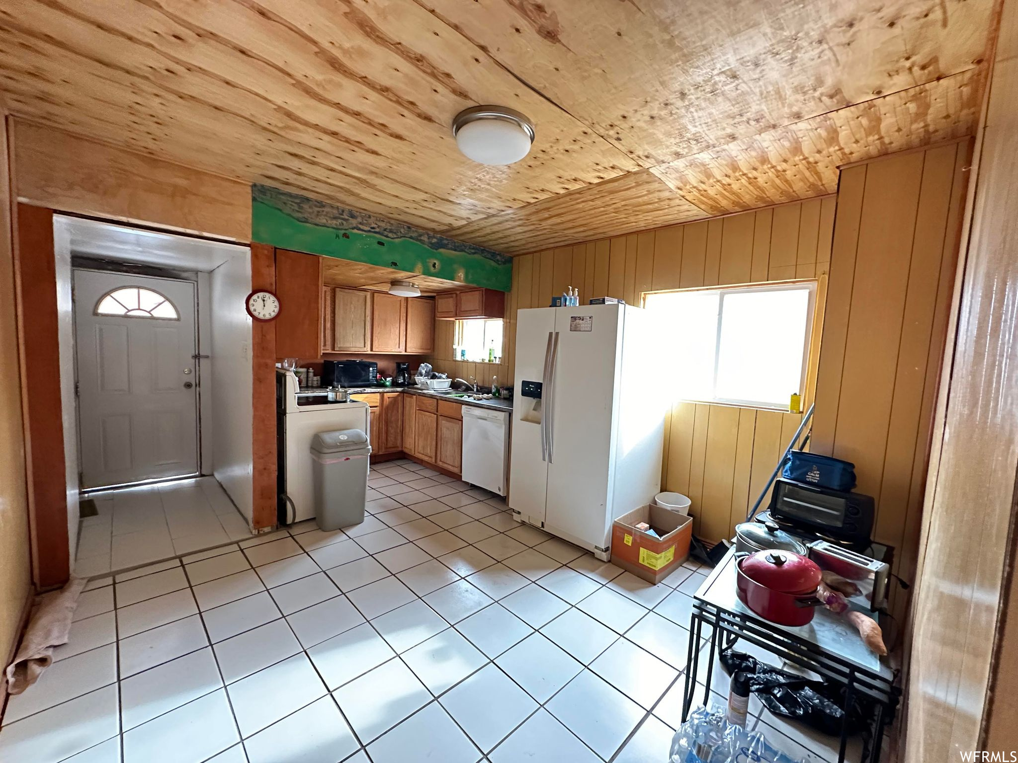 Kitchen with light tile floors, wooden ceiling, white appliances, and plenty of natural light