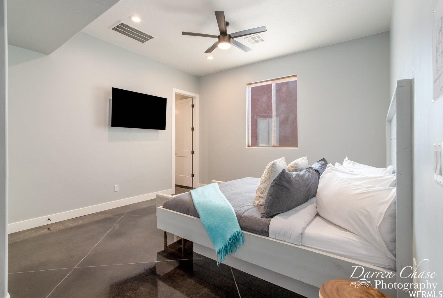 Tiled bedroom with a ceiling fan and TV