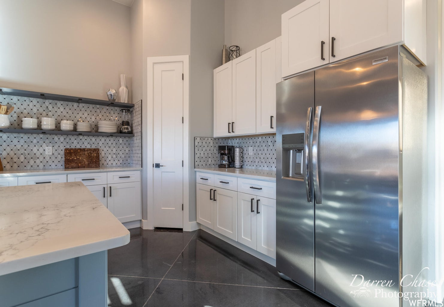 Kitchen featuring refrigerator, light countertops, white cabinetry, and dark tile floors