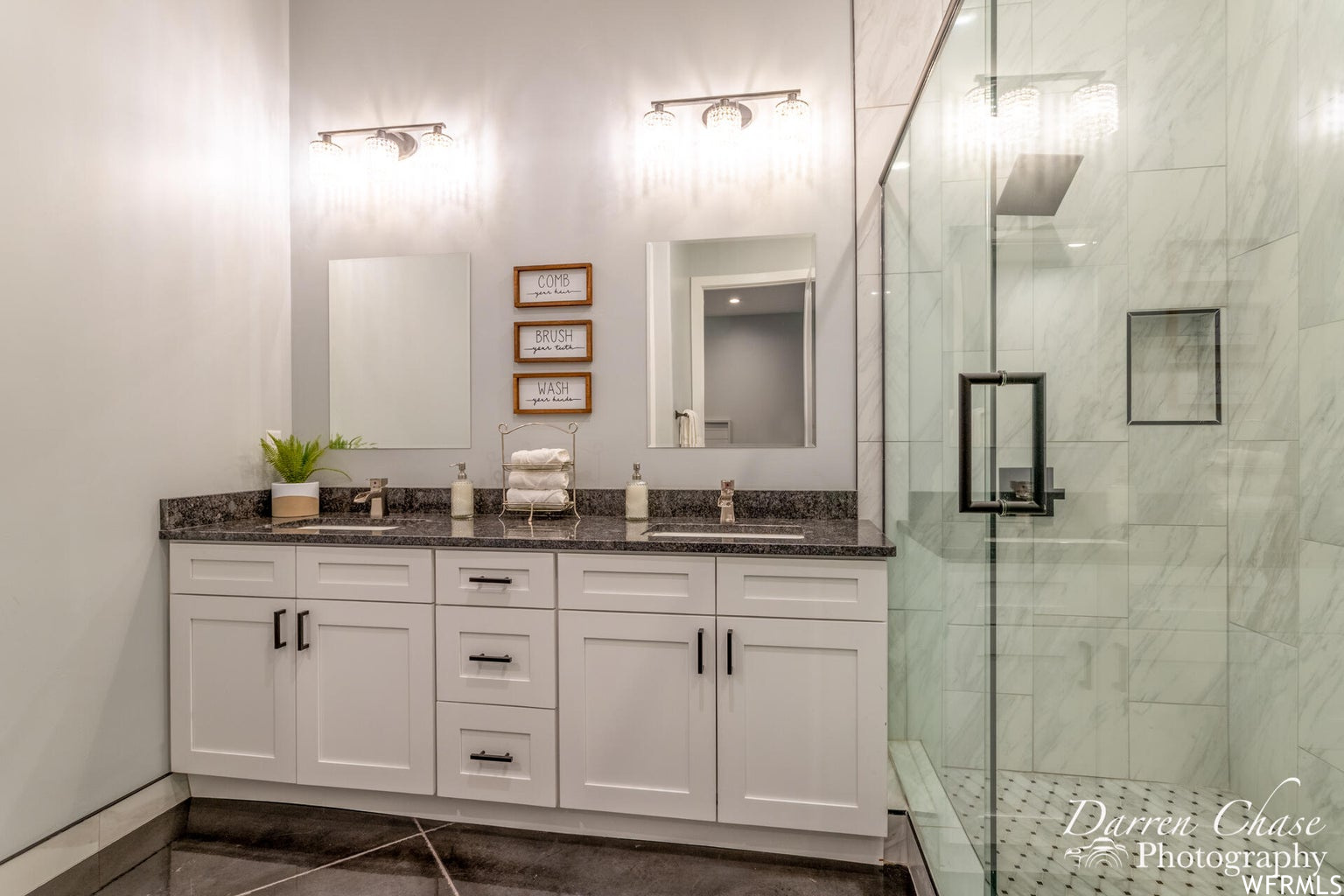 Bathroom featuring tile flooring, shower cabin, double vanities, and mirror