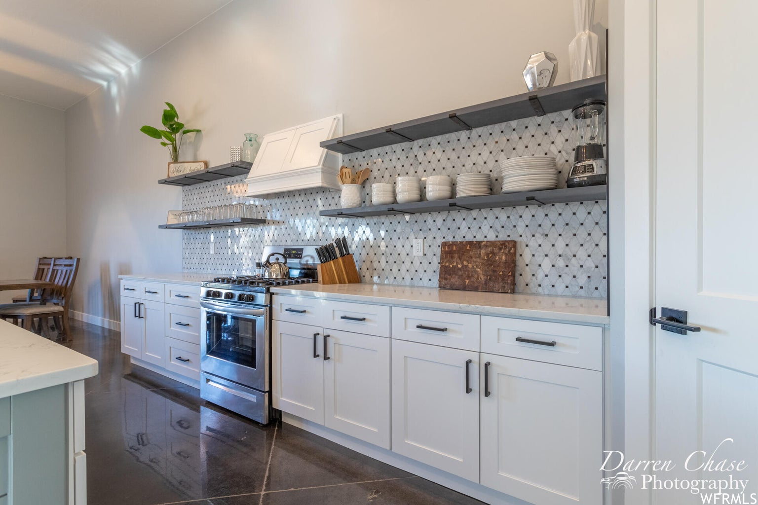 Kitchen featuring gas range oven, stainless steel finishes, light countertops, and white cabinets