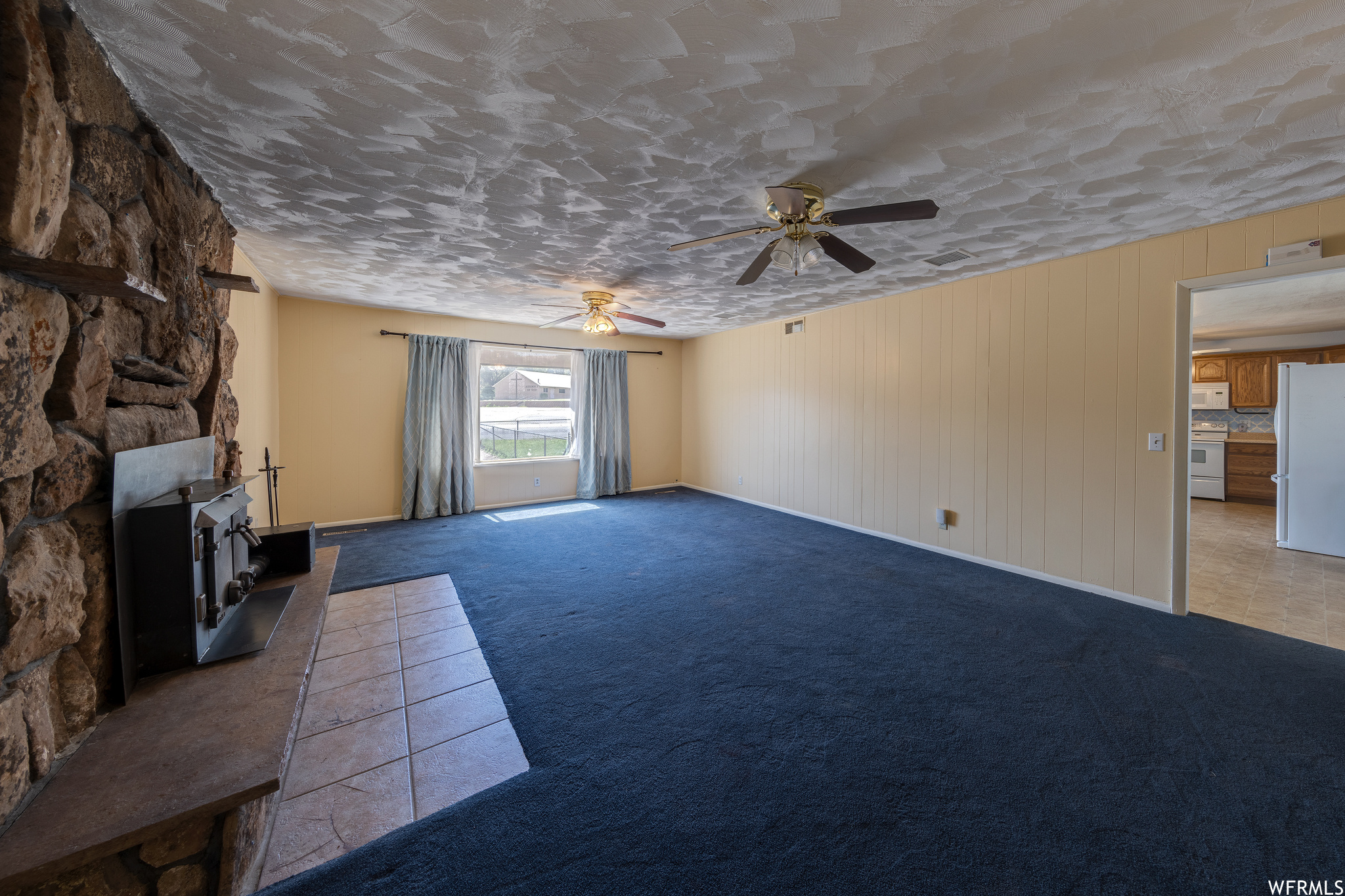 Carpeted living room with natural light and a ceiling fan