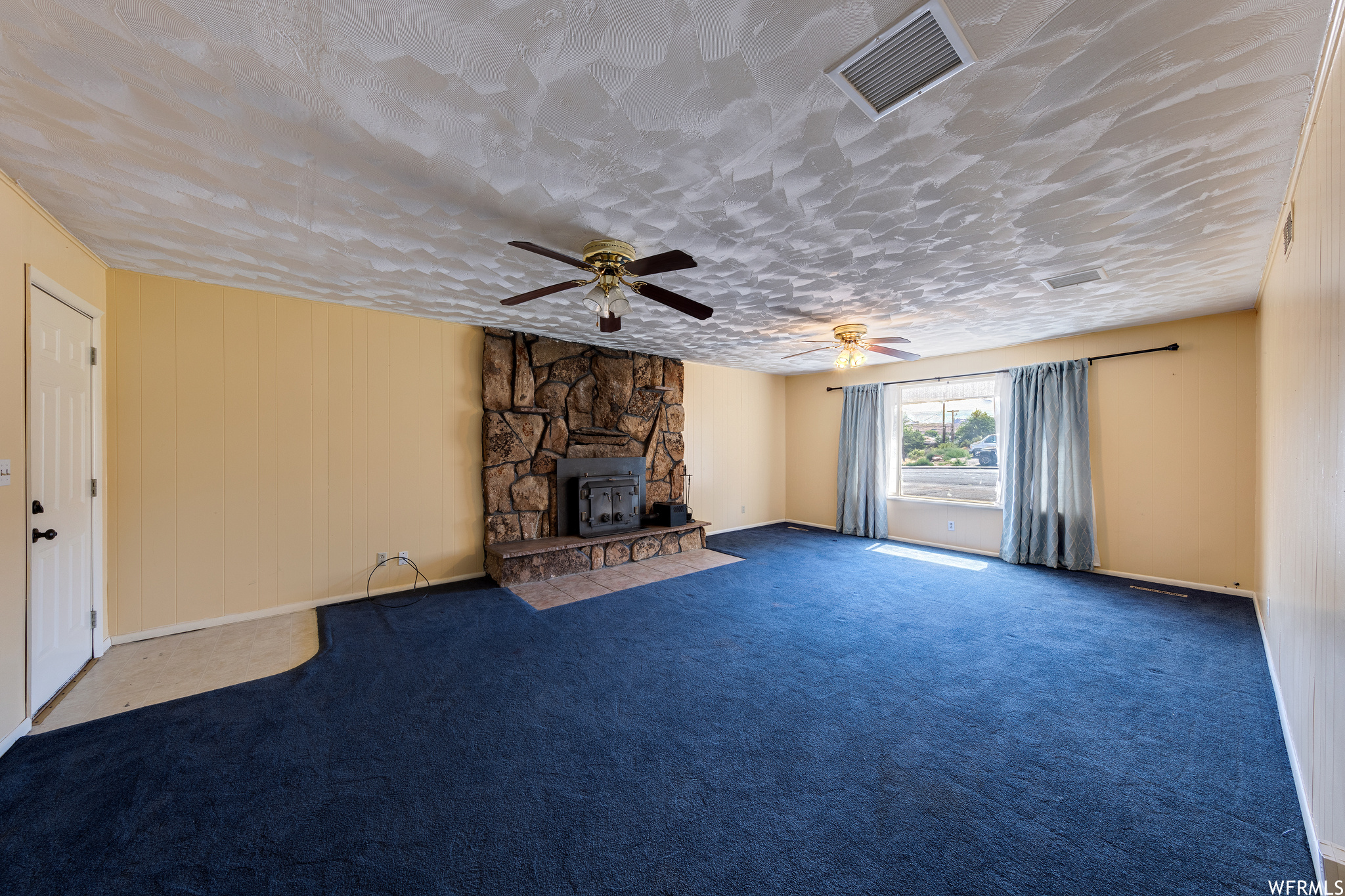 Carpeted living room with a fireplace, natural light, and a ceiling fan