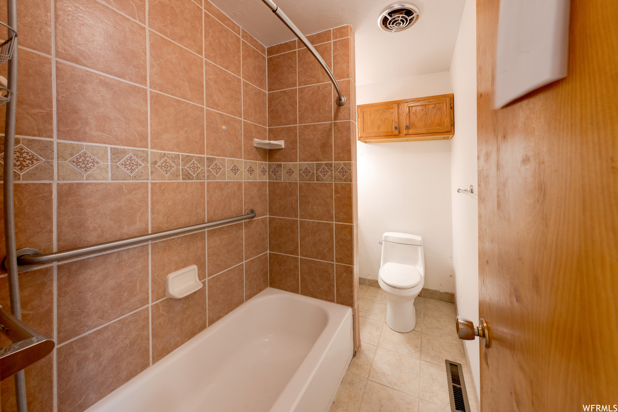 Bathroom with tile flooring, toilet, and shower / bathing tub combination
