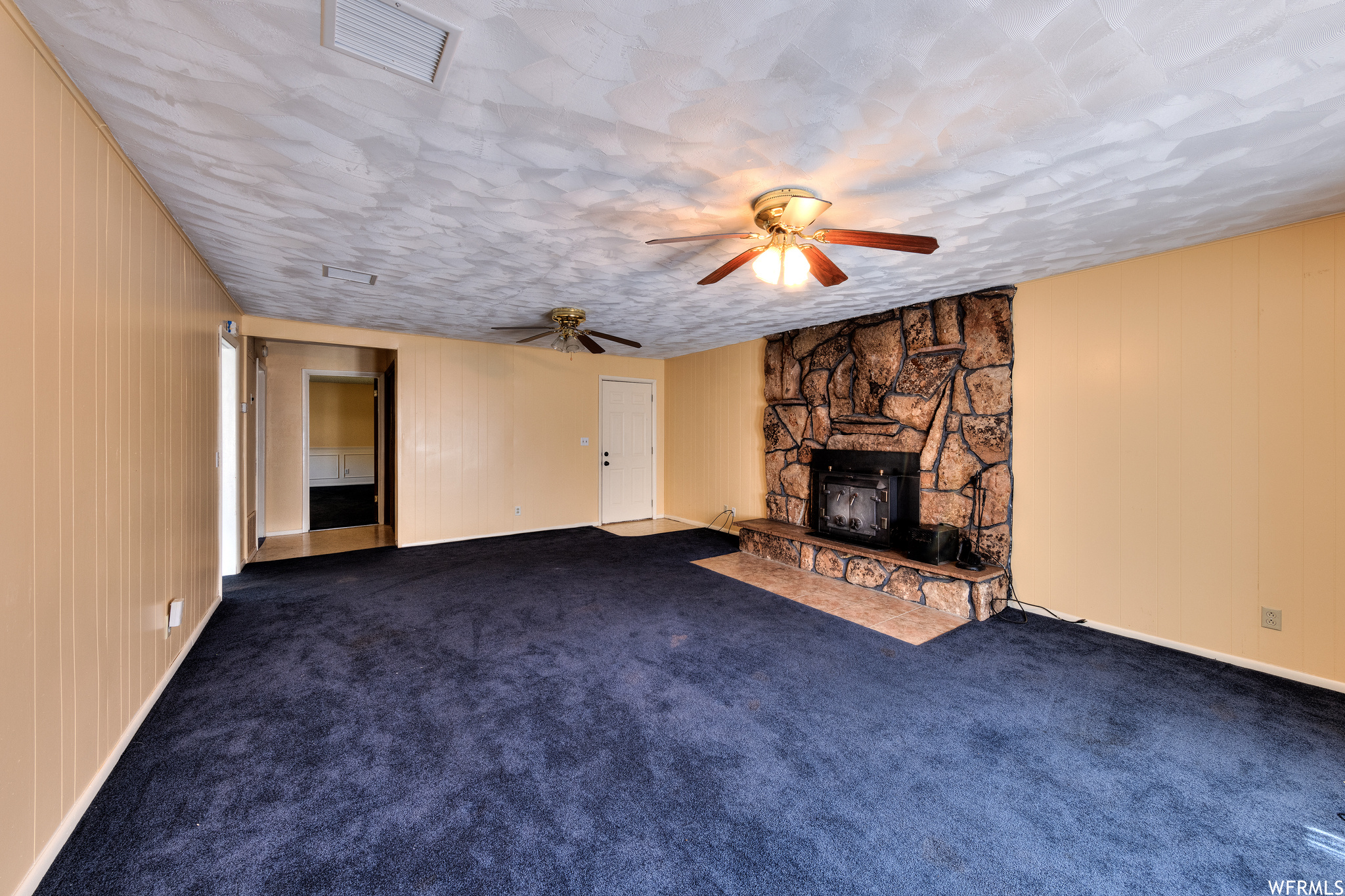 Living room with a fireplace, a ceiling fan, and carpet