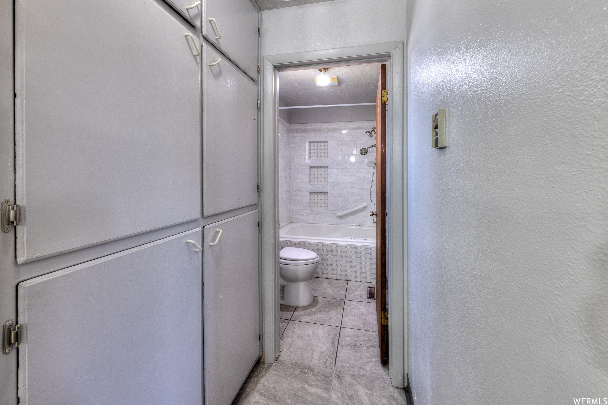 Bathroom featuring tile flooring, toilet, and bathing tub / shower combination
