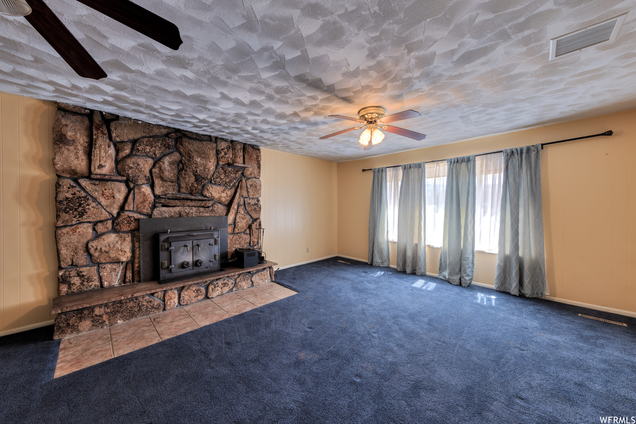 Living room featuring a fireplace, natural light, a ceiling fan, and carpet