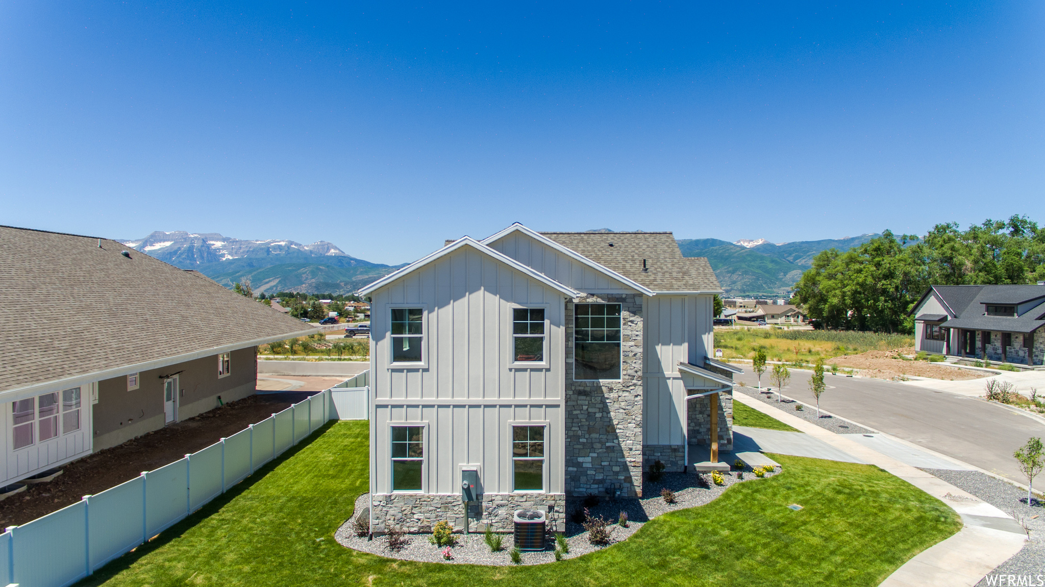 View of the side of the home featuring a mountain view, central AC, and a front lawn