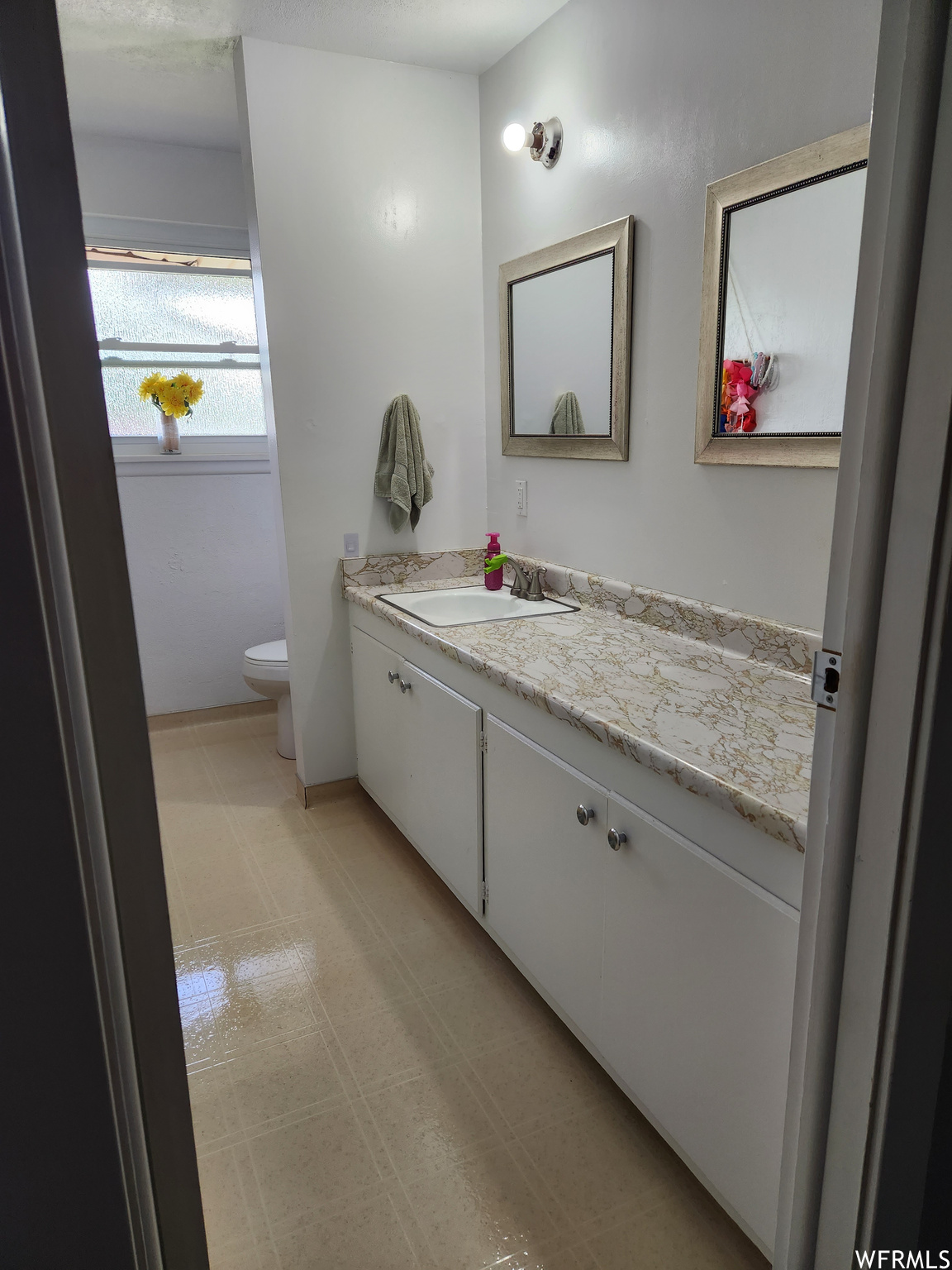 Bathroom featuring large vanity, mirror, and light tile floors