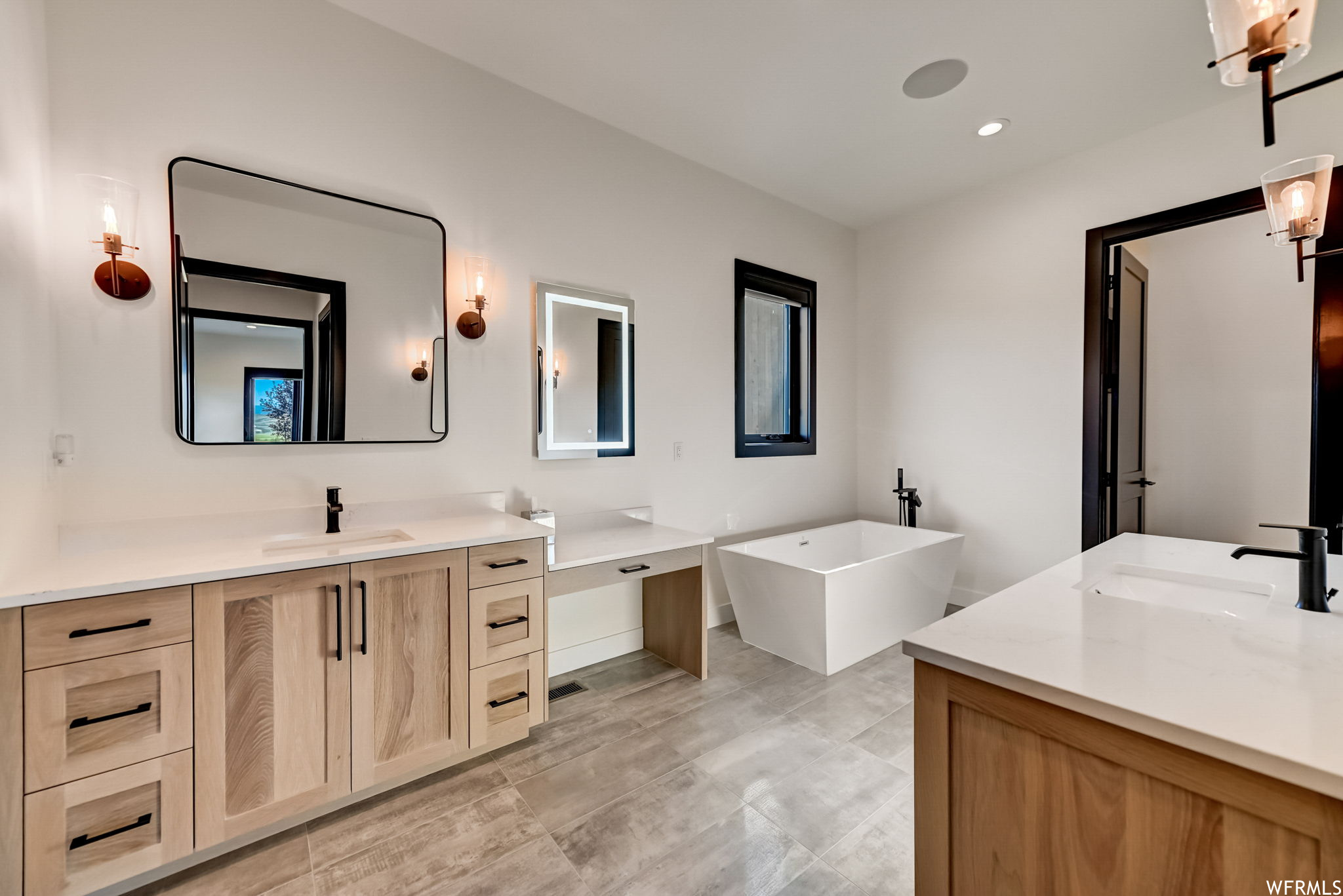 Bathroom featuring double sink, tile floors, a tub, and vanity with extensive cabinet space