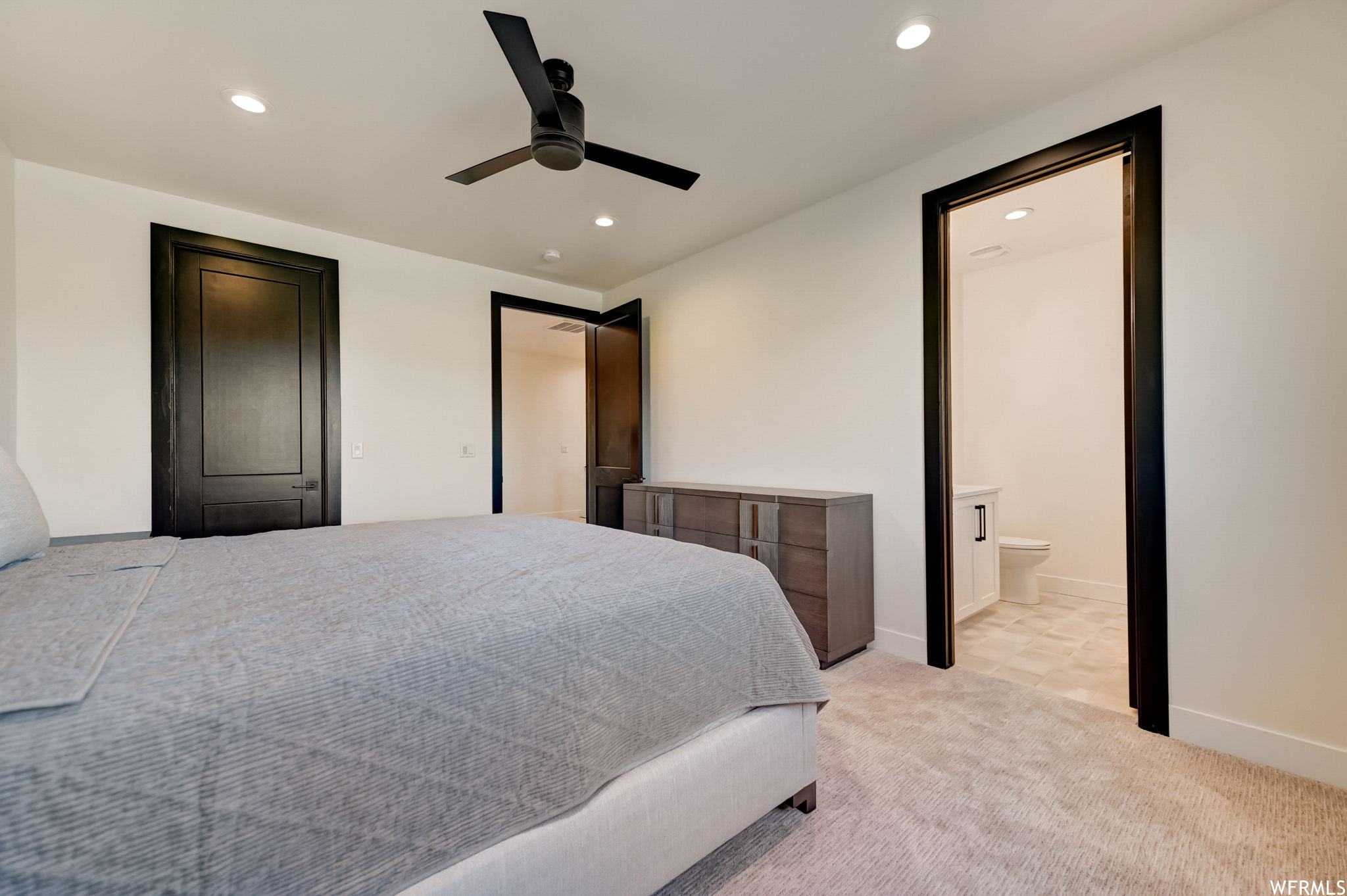 Bedroom featuring connected bathroom, light carpet, and ceiling fan