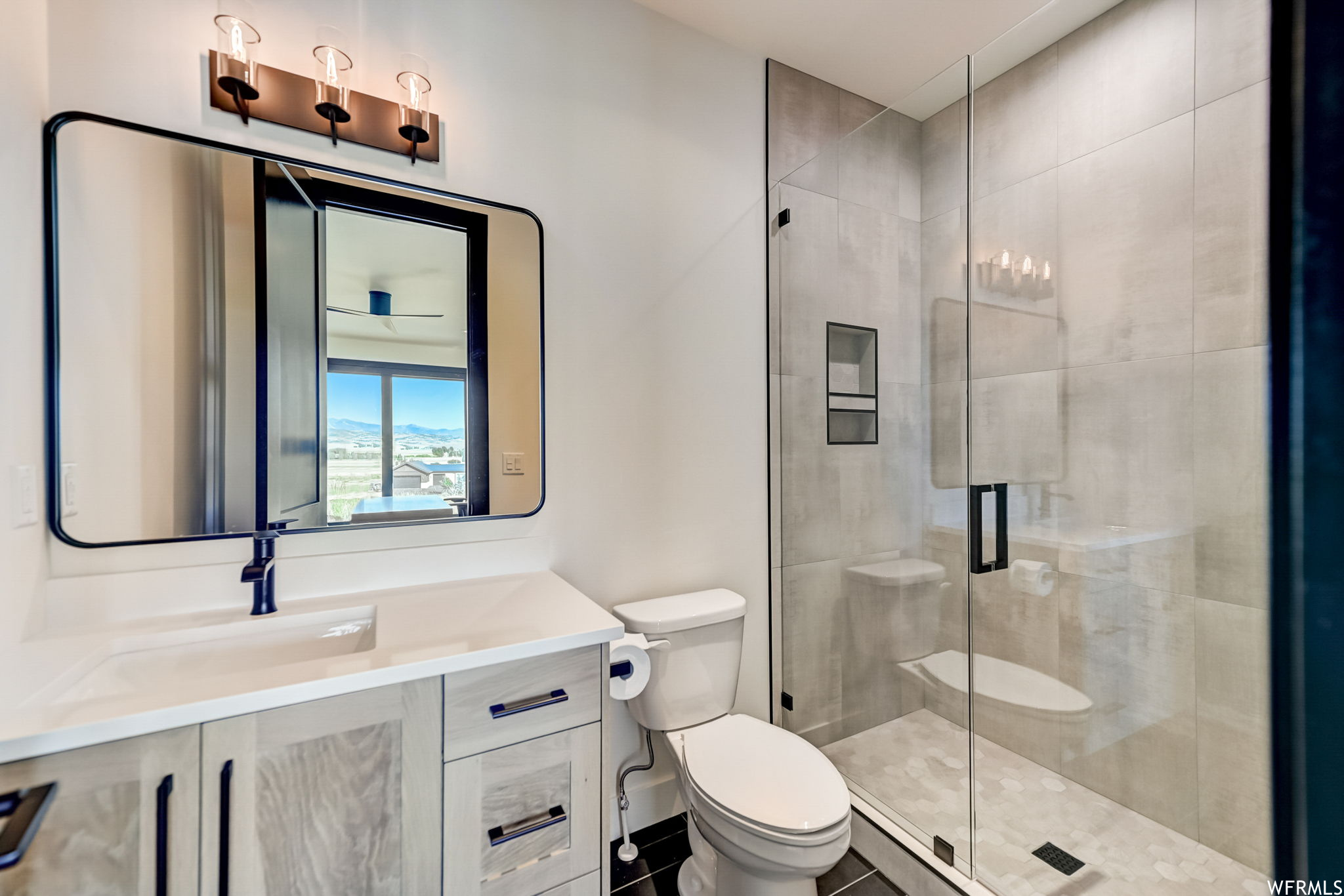 Bathroom featuring vanity, walk in shower, tile flooring, and toilet
