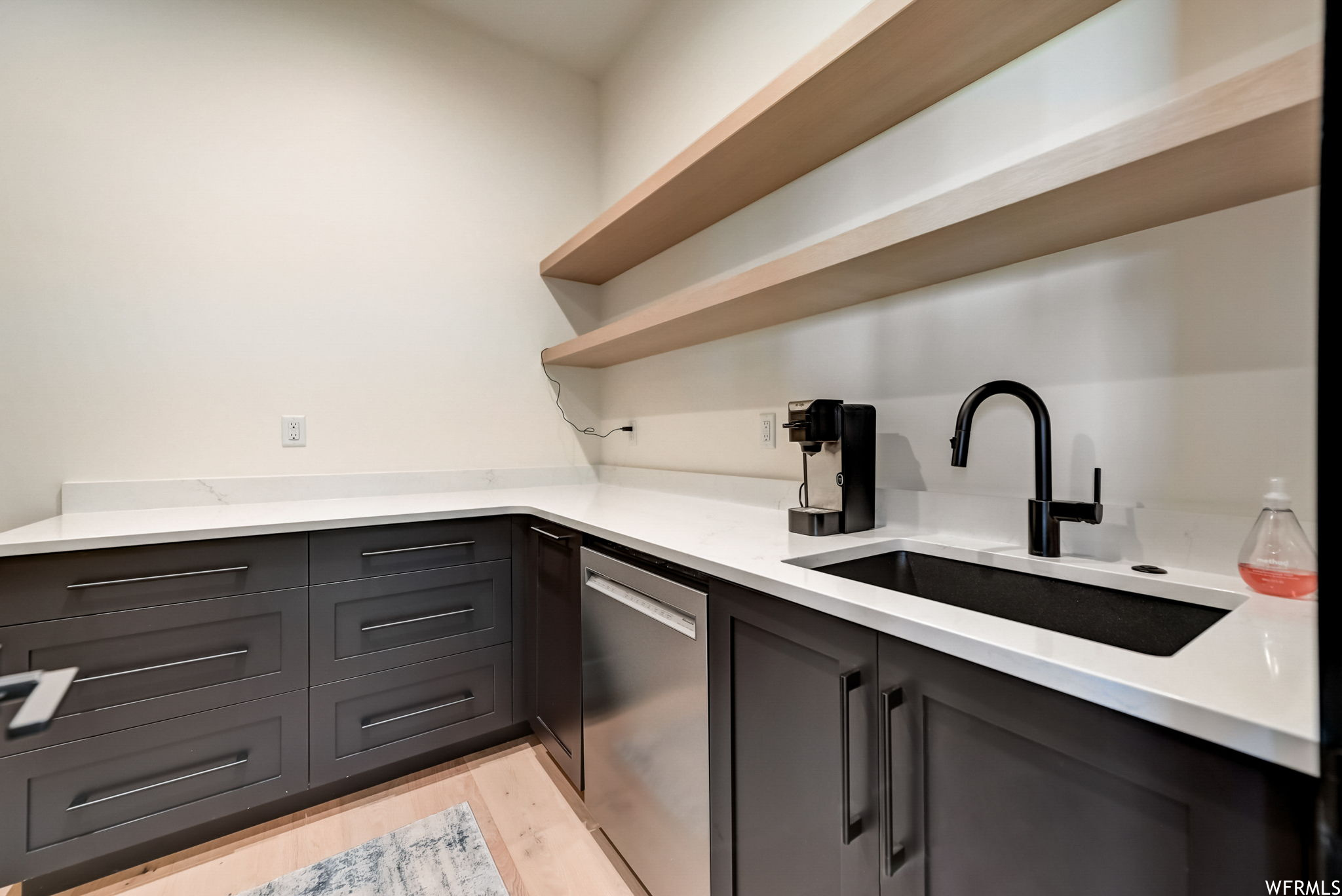 Kitchen featuring sink, dishwasher, gray cabinetry, and light hardwood / wood-style floors