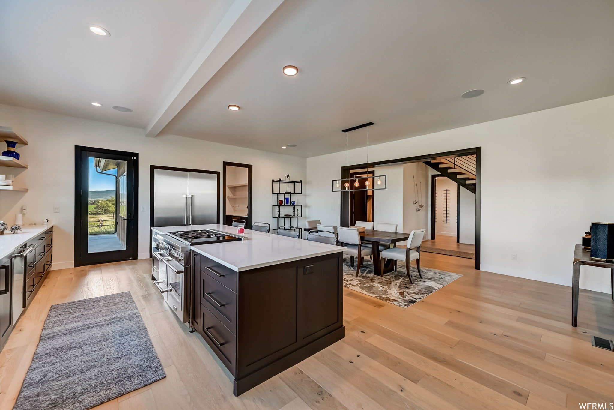 Kitchen featuring premium appliances, pendant lighting, dark brown cabinets, a center island, and light wood-type flooring