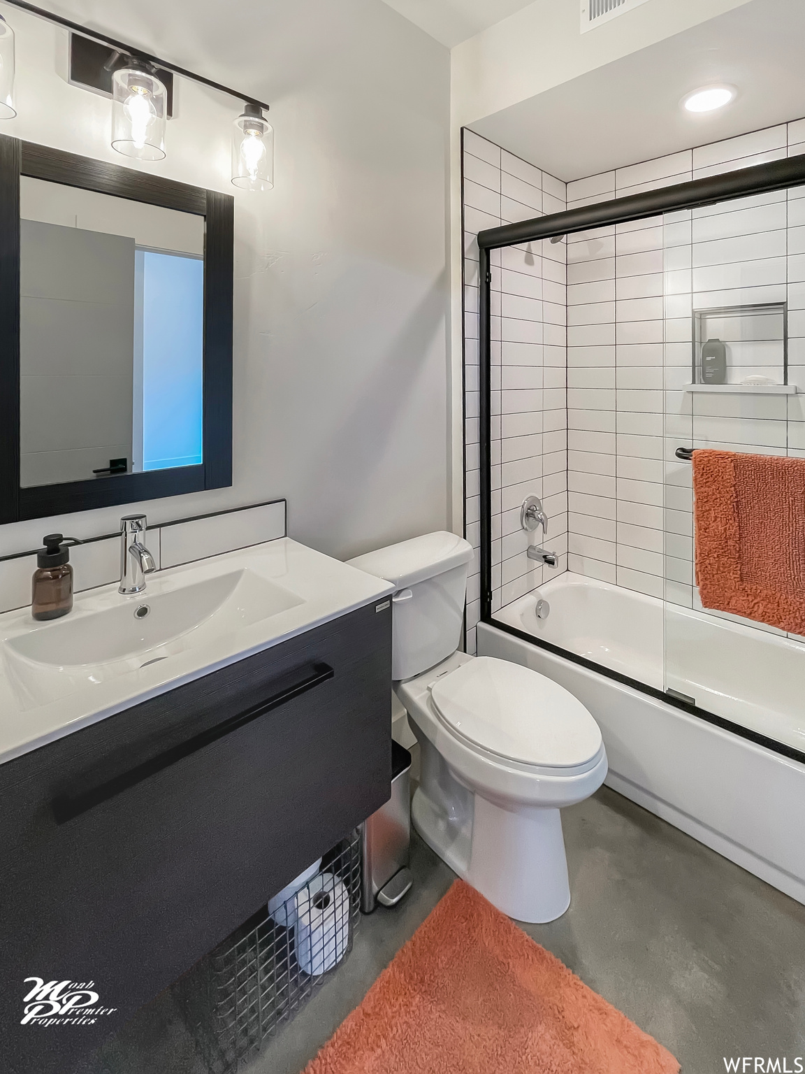 Full bathroom featuring vanity, bath / shower combo with glass door, concrete floors, and mirror