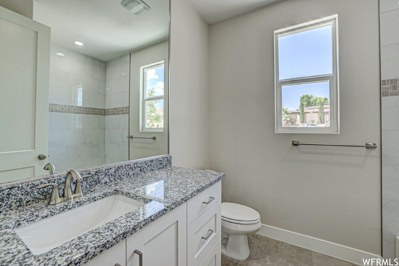 Bathroom with vanity with extensive cabinet space, mirror, and light tile floors