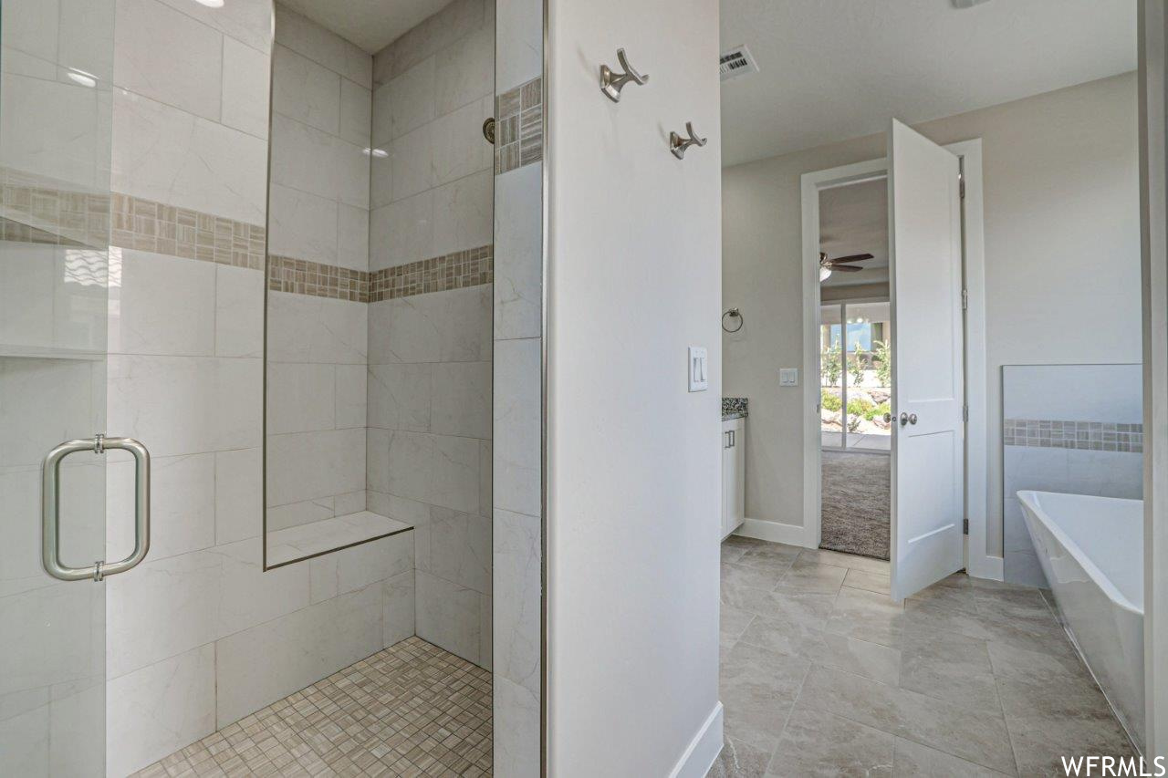 Bathroom featuring vanity, separate shower and tub enclosures, ceiling fan, and light tile flooring