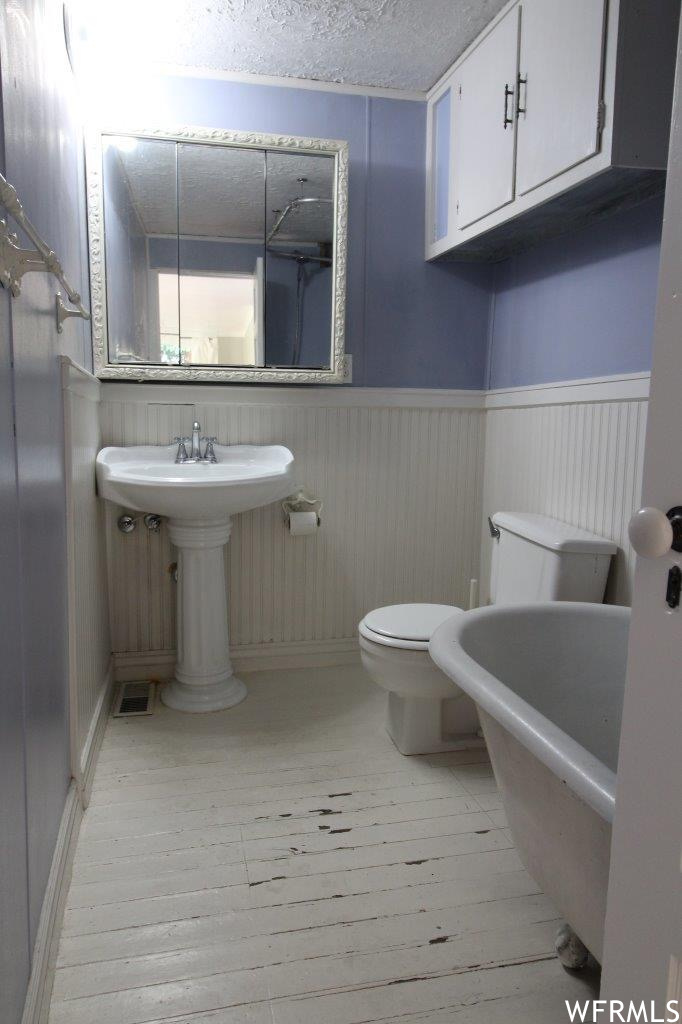Full bath downstairs still has original farmhouse vibe with painted wood floors, beaded wainscoting, and original clawfoot tub.