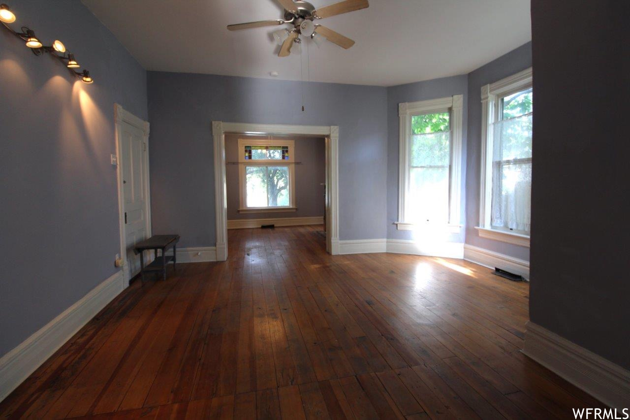 Another angle / view of the big living room area on the main floor and through to the parlor with original turn-of-the-century plank wood floors.