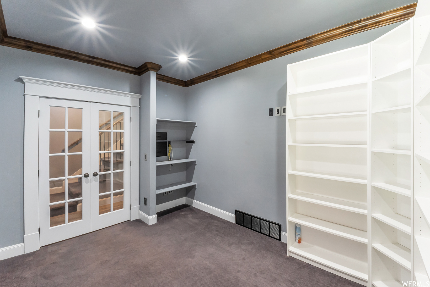 Office with custom built in bookshelves and french doors.
