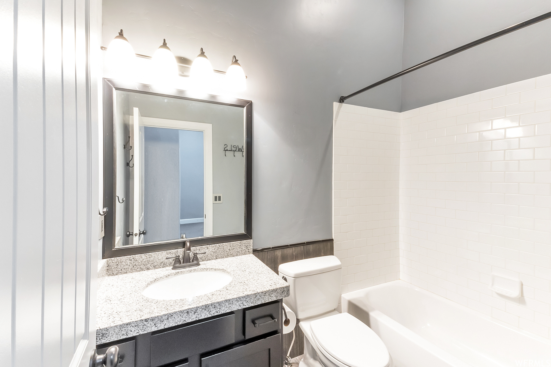Full bathroom featuring granite vanity with extensive cabinet space, mirror, and tiled shower / bath