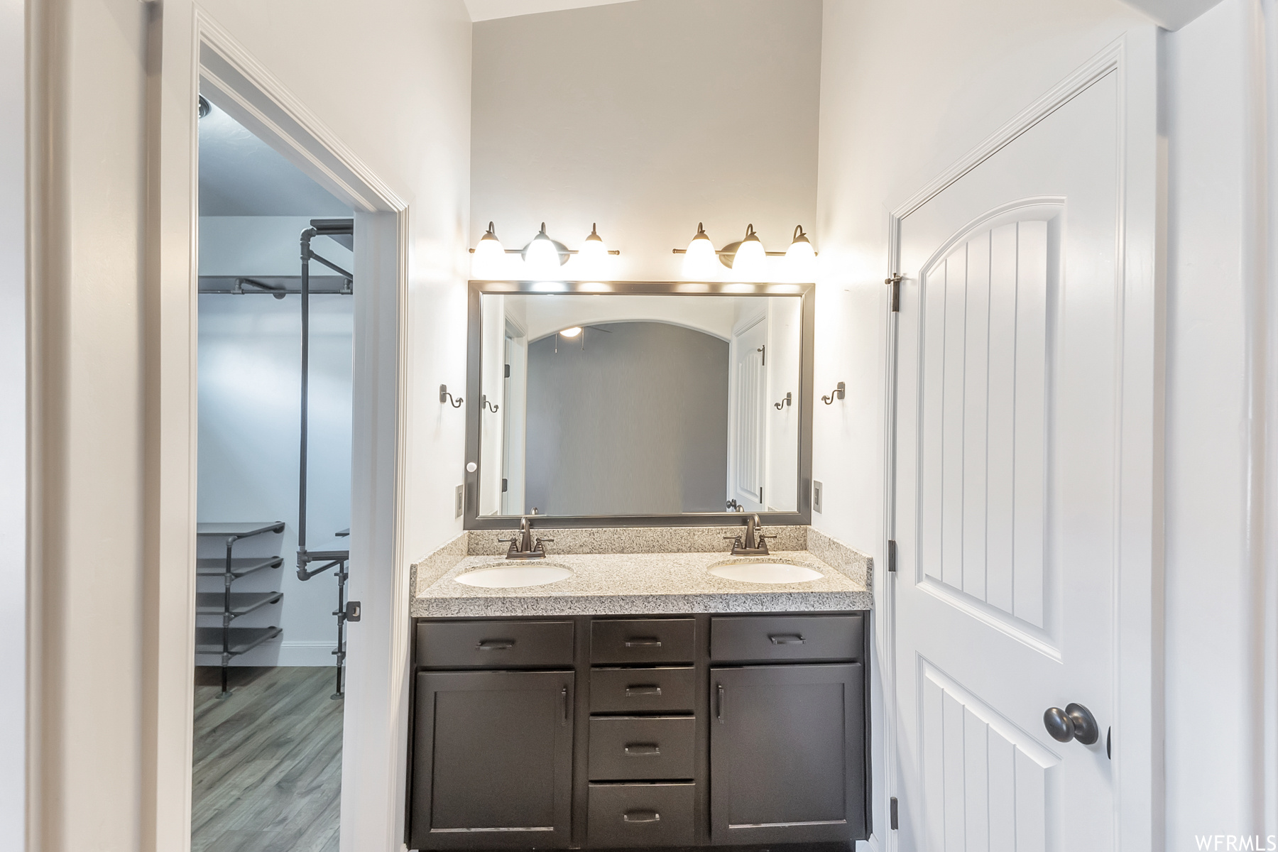 Bathroom with dual large vanity, mirror, and light hardwood floors