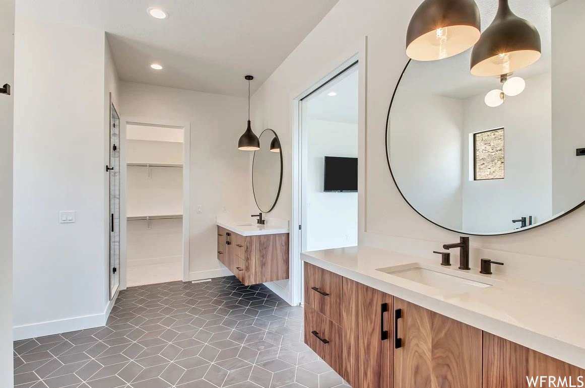 Bathroom featuring light tile floors, dual bowl vanity, and mirror