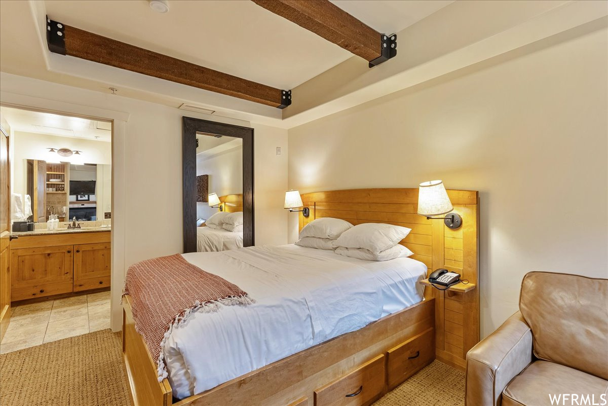 Tiled bedroom featuring a raised ceiling and beam ceiling