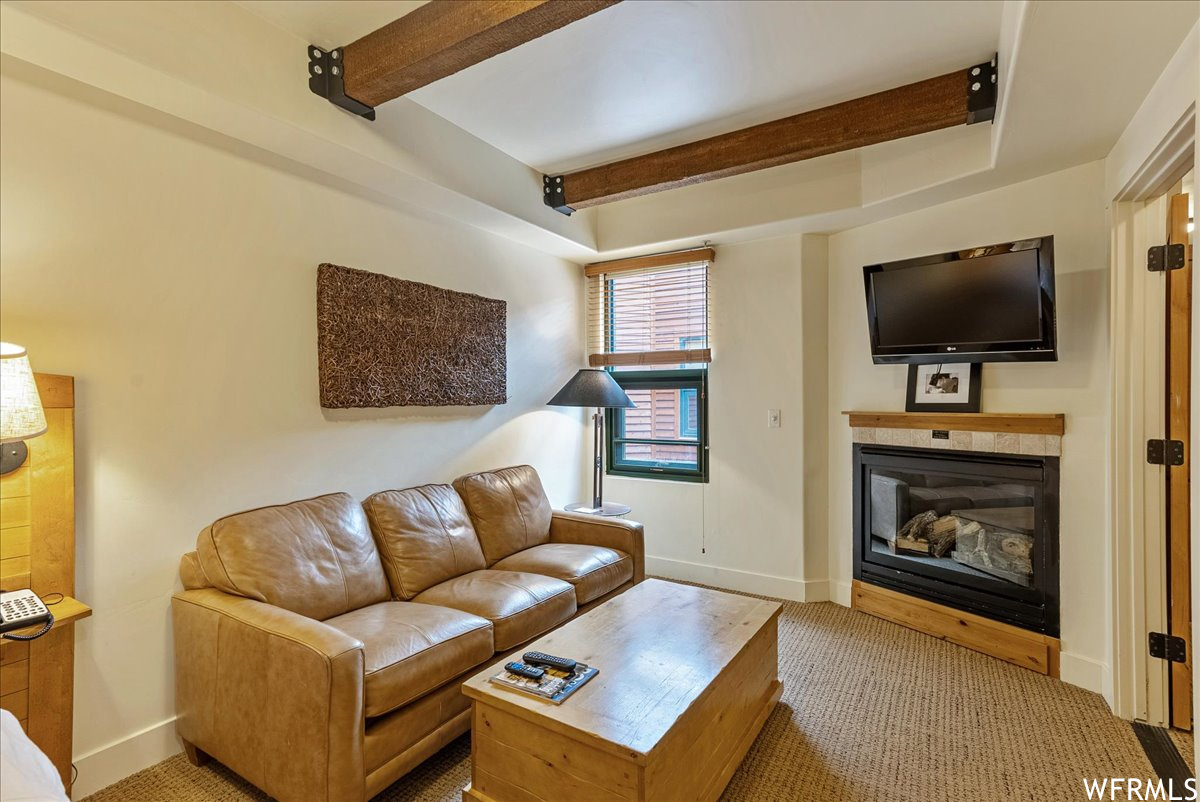 Carpeted living room with a fireplace and beam ceiling
