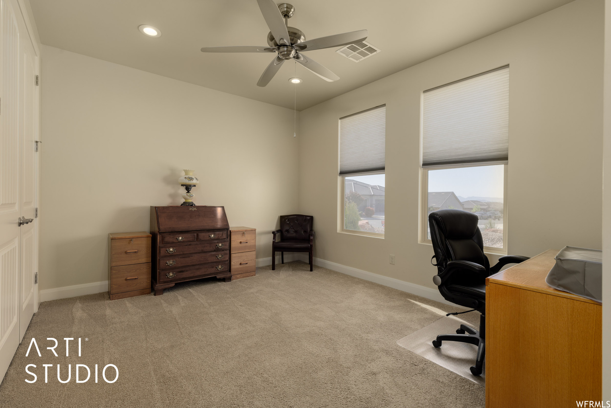 Carpeted office/bedroom featuring ceiling fan