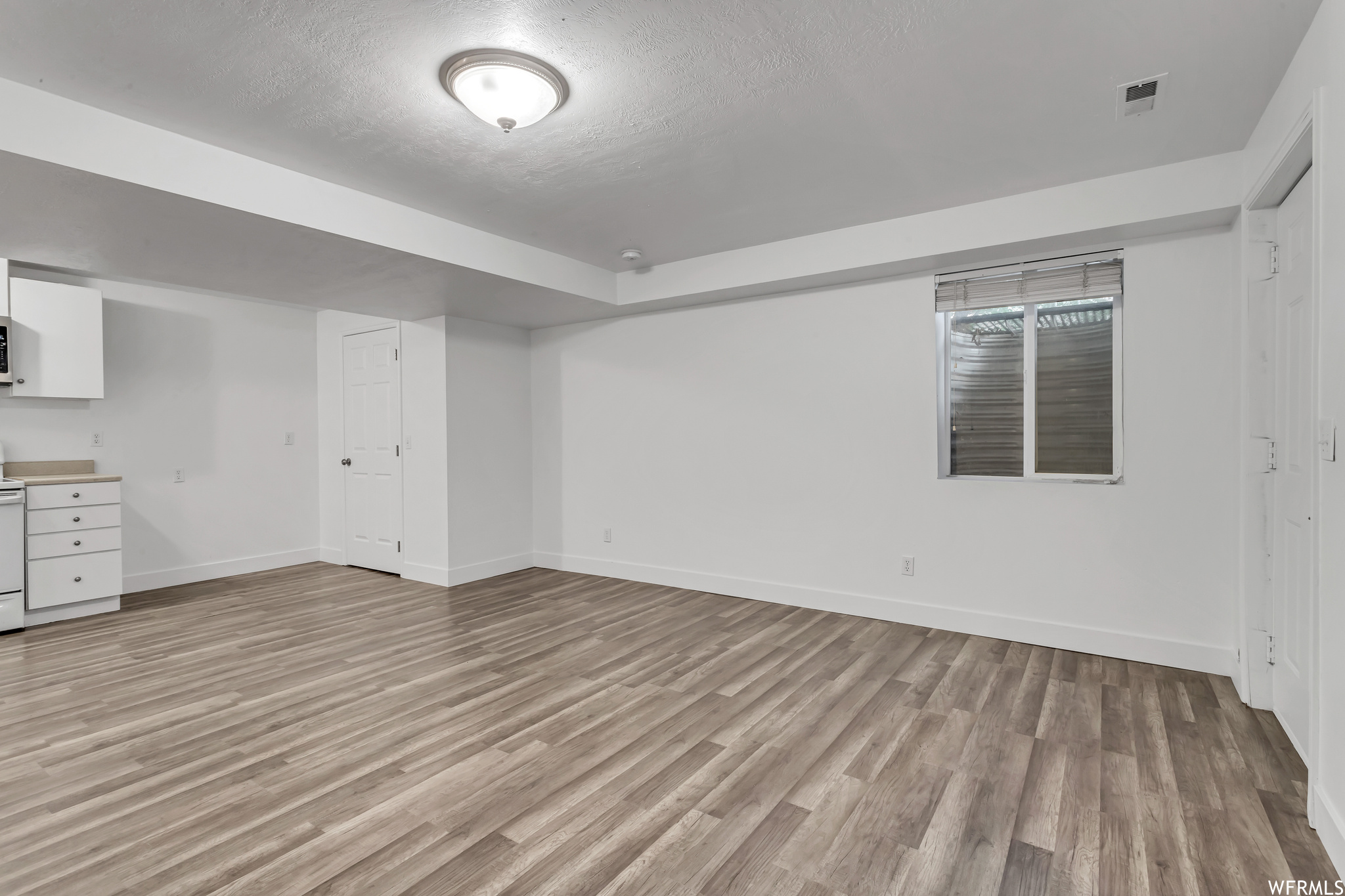 Basement with a textured ceiling and light hardwood floors