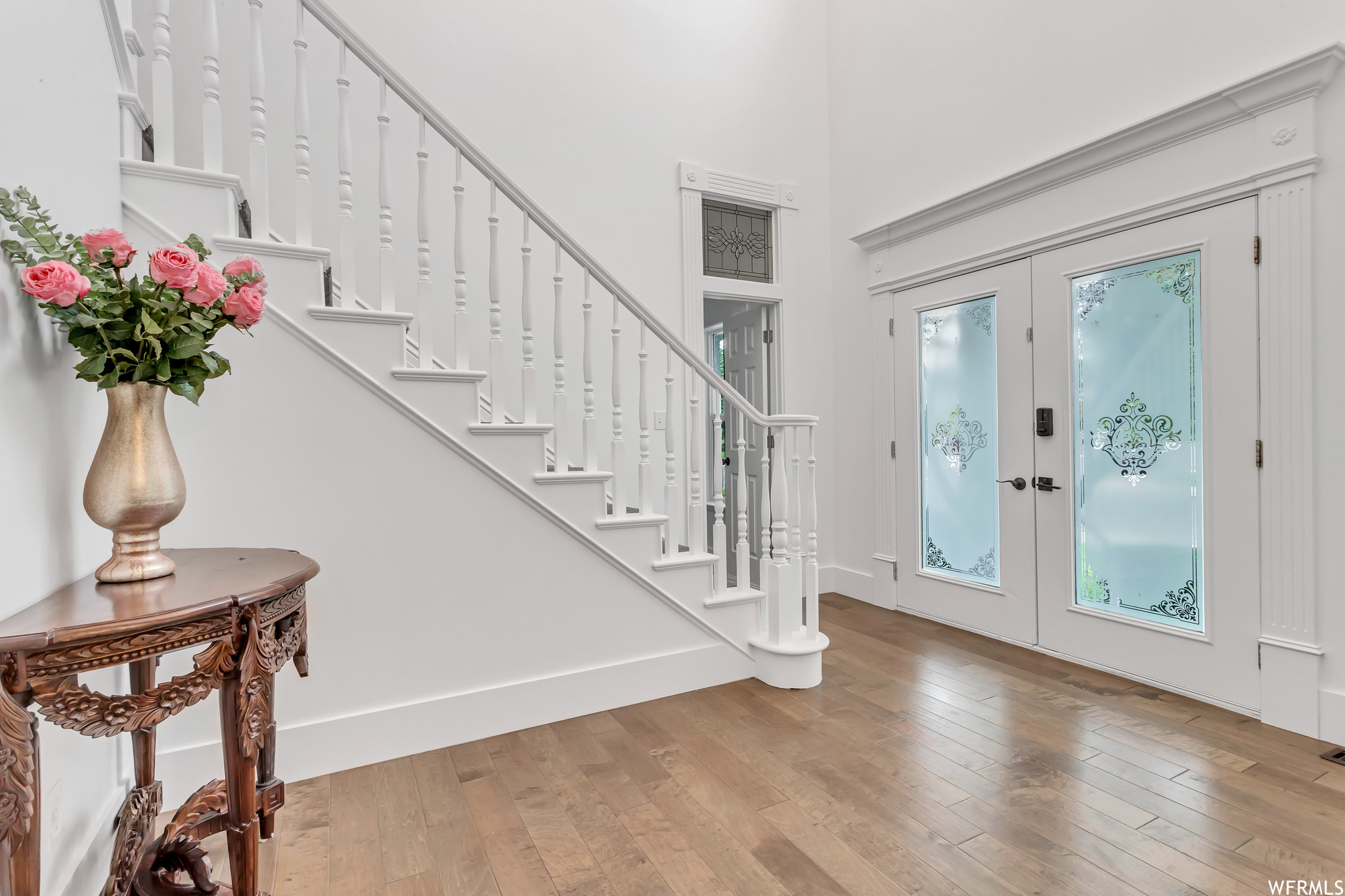Hardwood floored foyer featuring french doors and a high ceiling