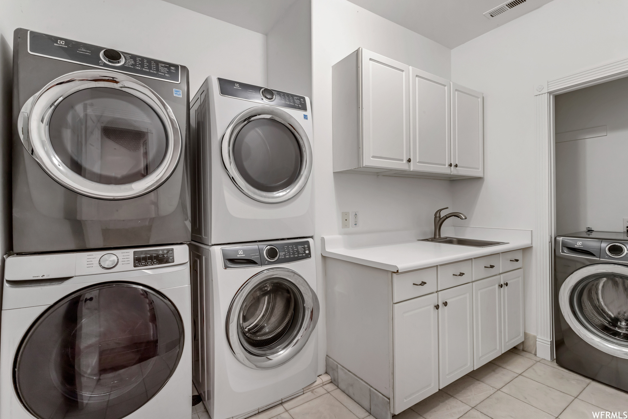 Laundry room with light tile floors, stacked washer and clothes dryer, and separate washer and dryer
