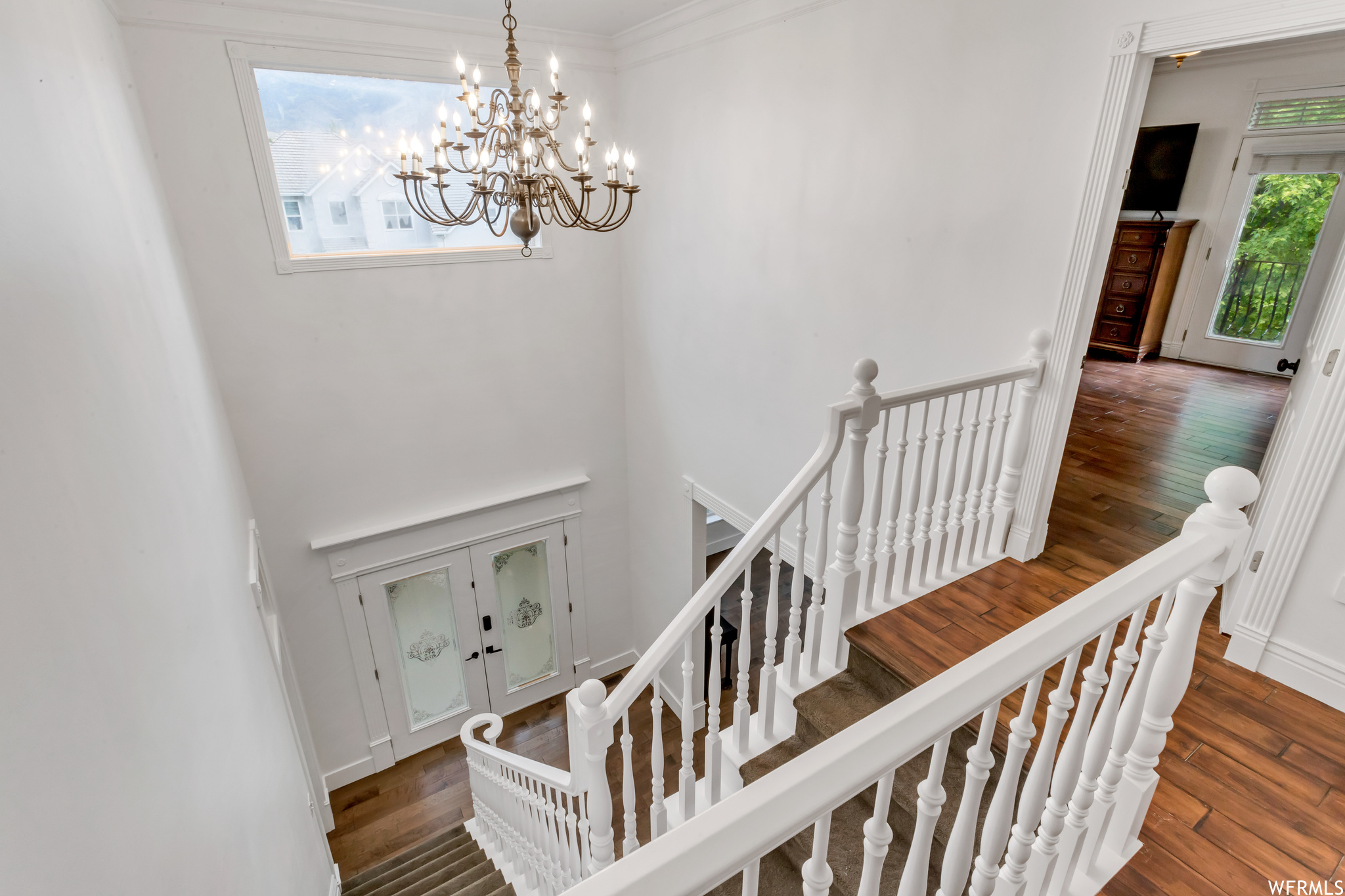 Stairway with ornamental molding, a high ceiling, and light hardwood flooring