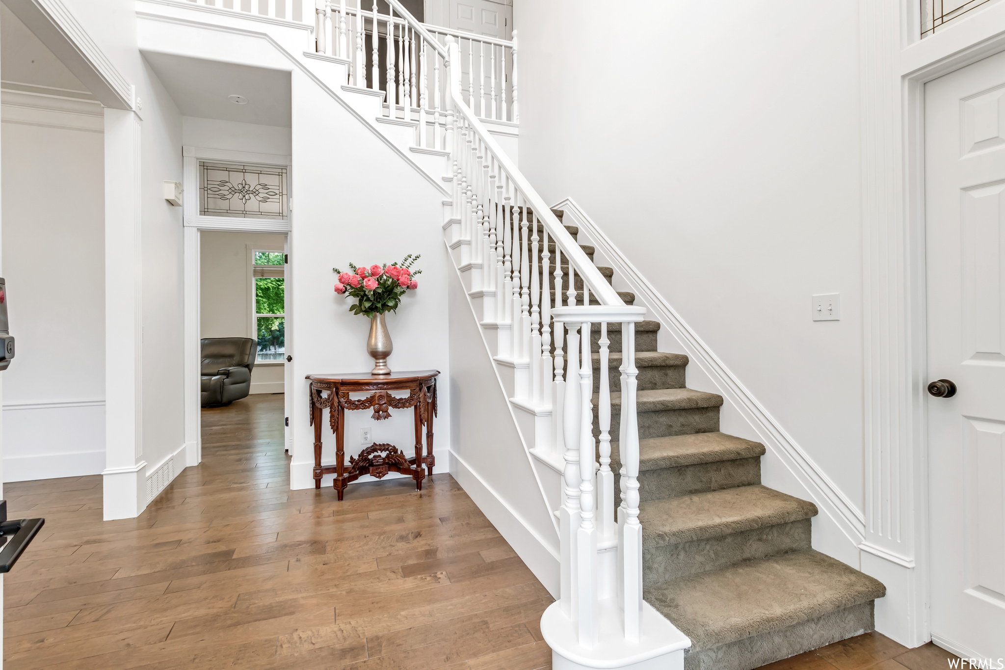 Stairs with light hardwood floors and a high ceiling