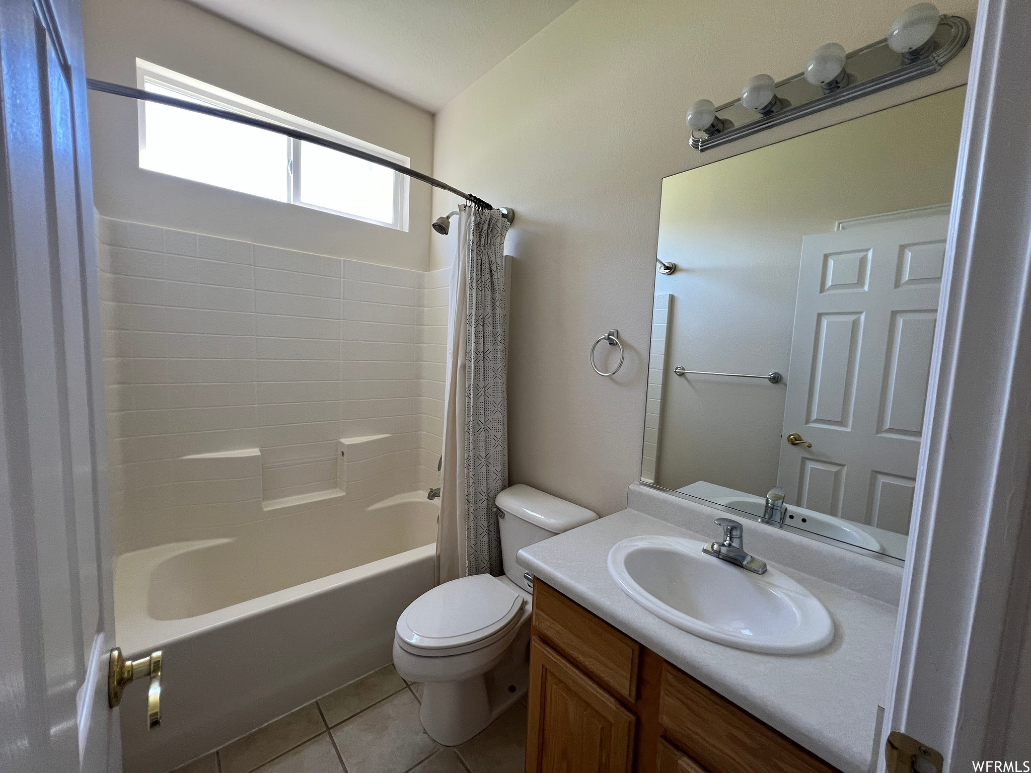 Full bathroom featuring vanity, shower / bath combo, tile flooring, and mirror