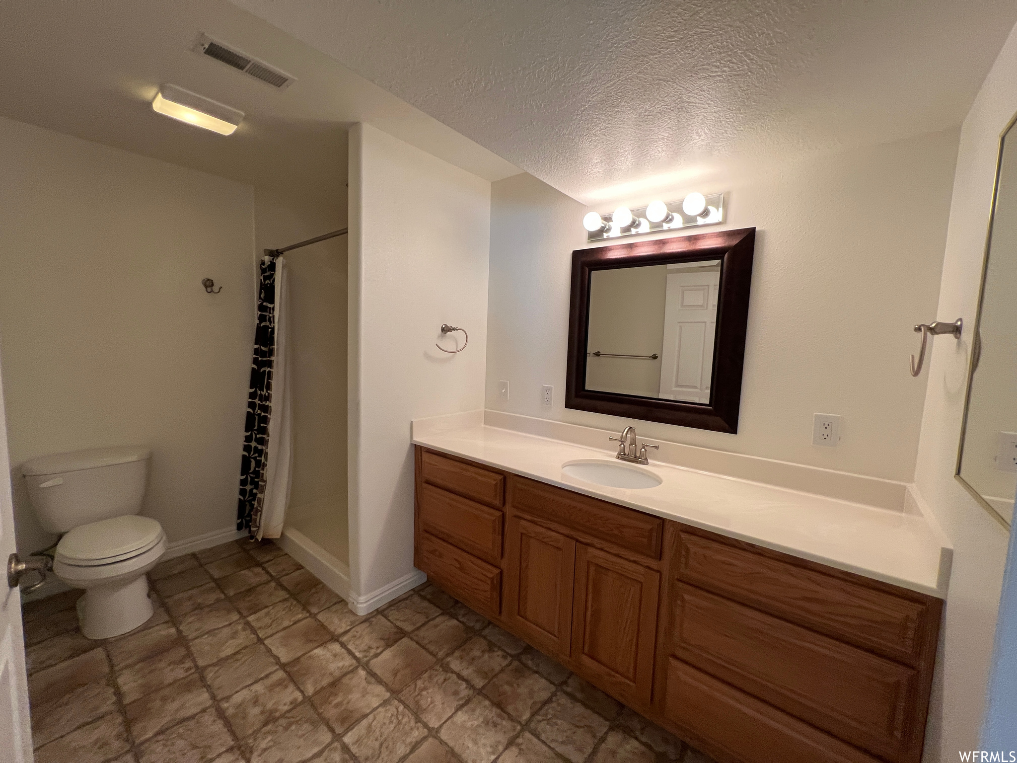 Bathroom featuring vanity, a textured ceiling, mirror, and tile flooring