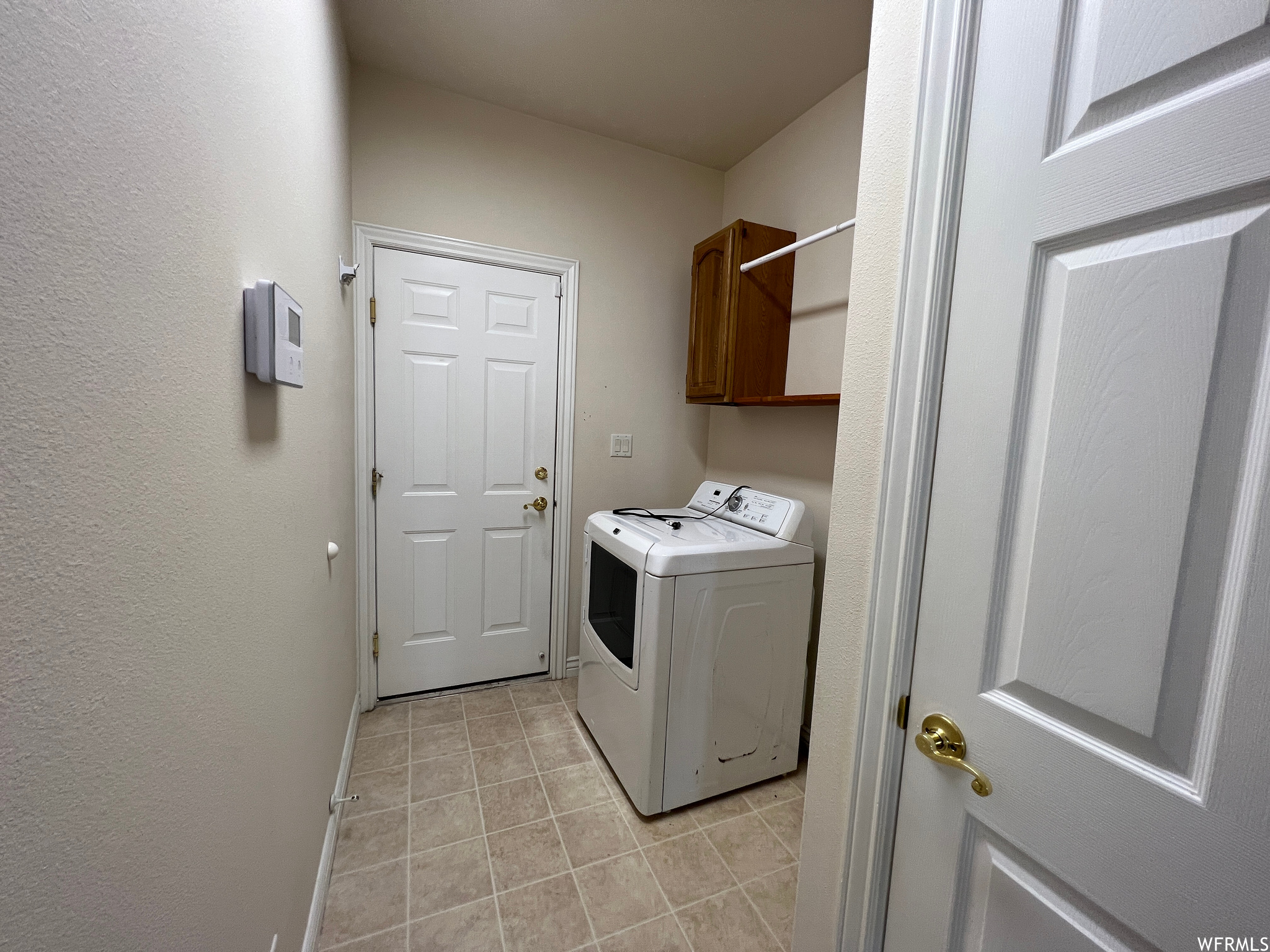 Clothes washing area featuring washer / clothes dryer and light tile floors